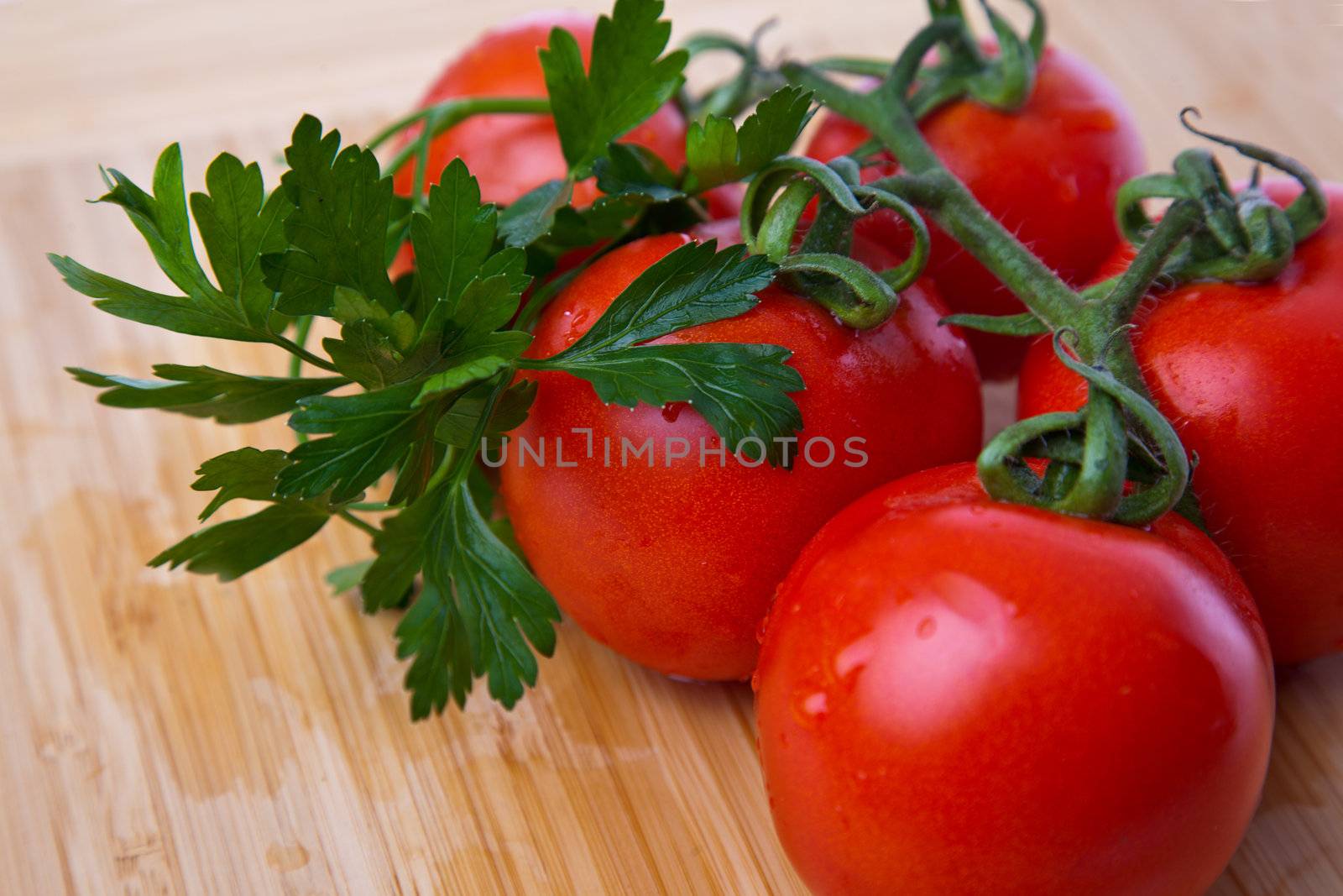 Close-up of parsley and fresh tomatoes branch on wooden board