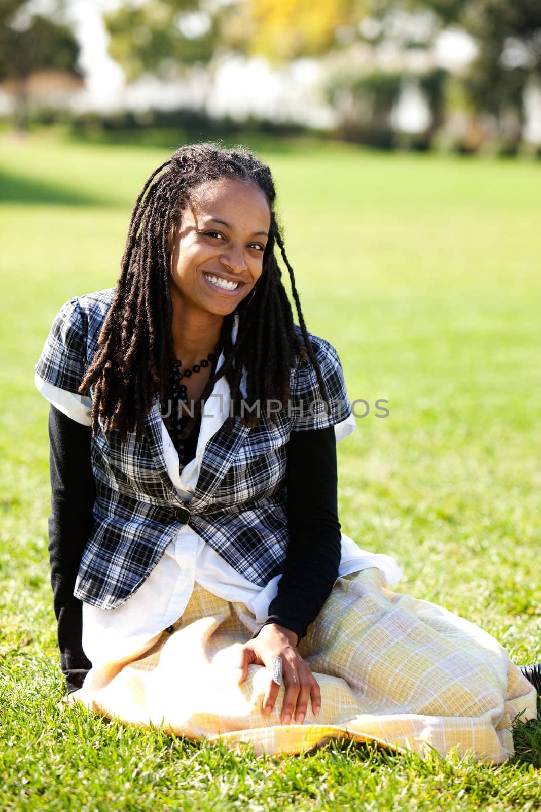 A young African American student sitting on grass