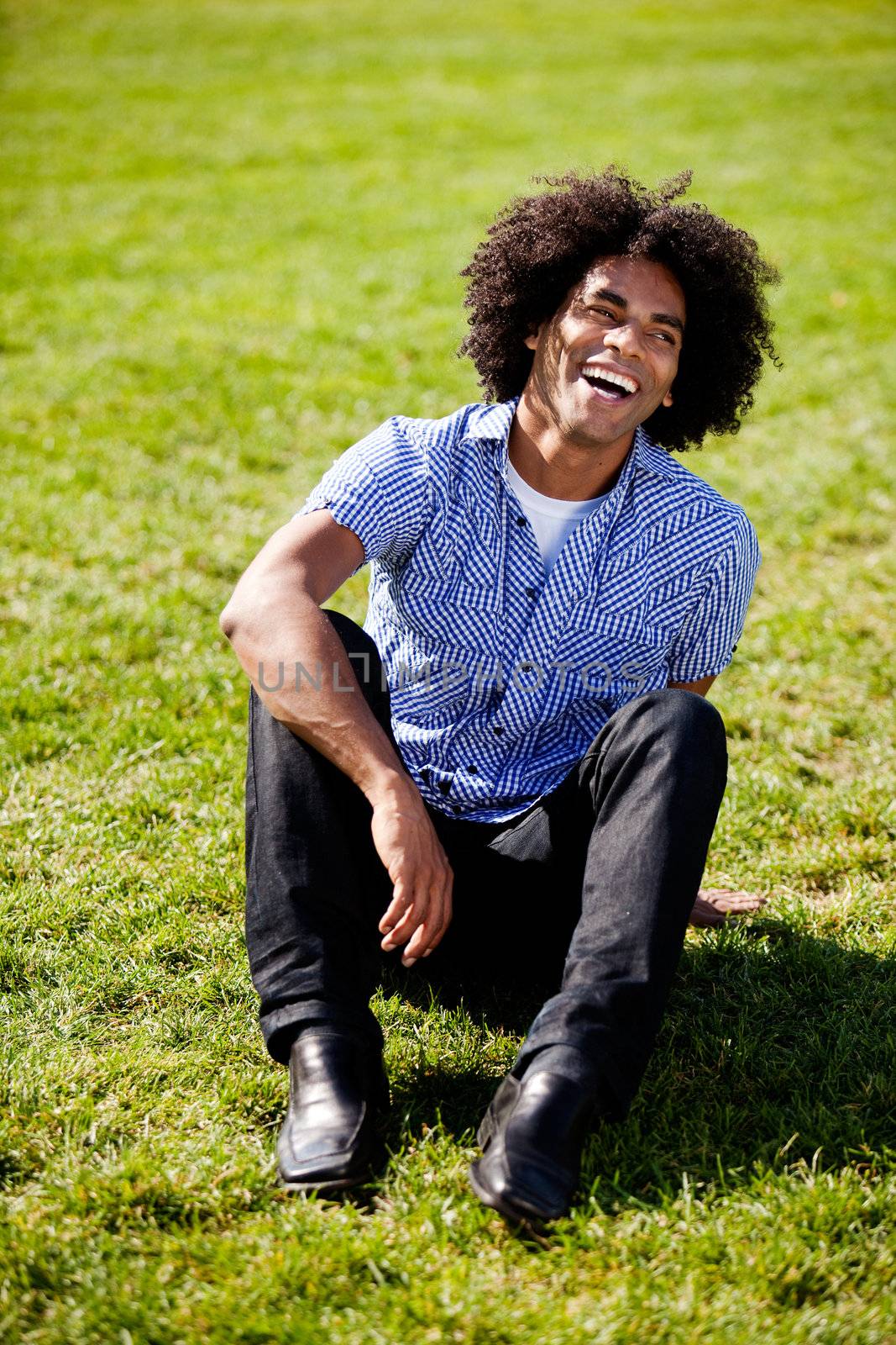 An African American sitting on grass with a natural laugh