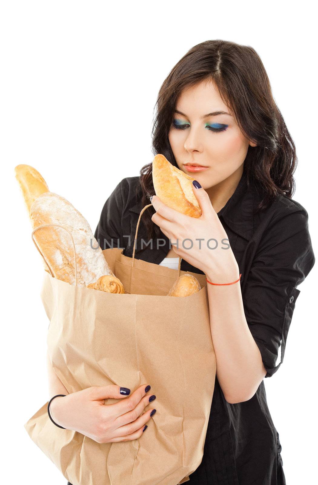Beautiful female holding shopping bag full of bread, smelling a small baguette