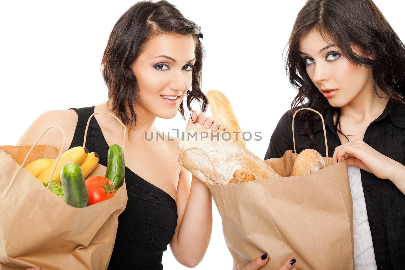 Two beautiful girlfriends holding shopping bags full of groceries, looking at camera