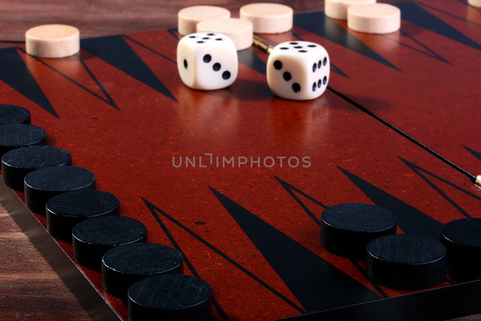 Backgammon, in the foreground in focus black counters, on a background of a counter of the contender and cubes.