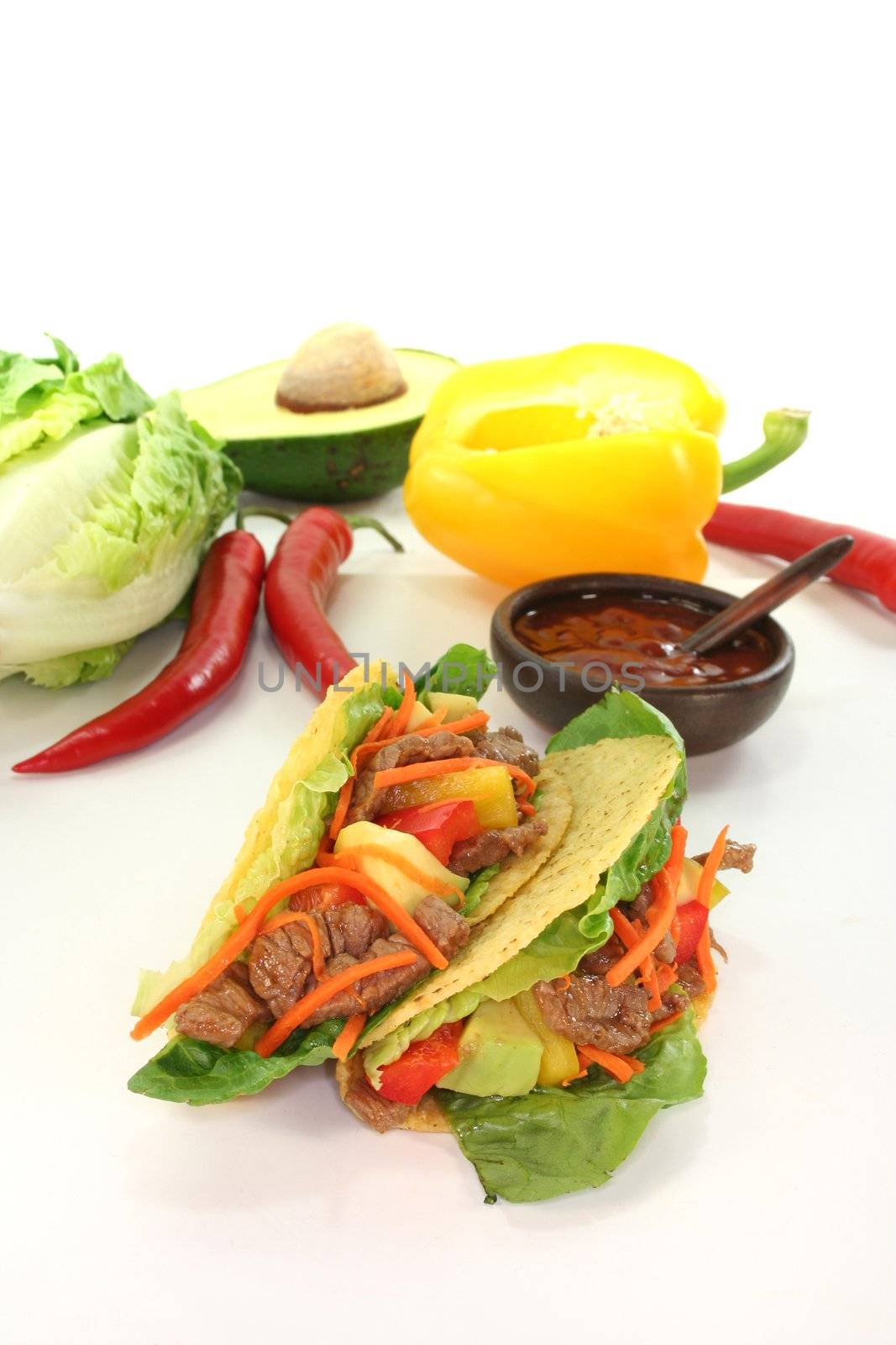 Mexican tacos with beef, lettuce, peppers and avocado on white background