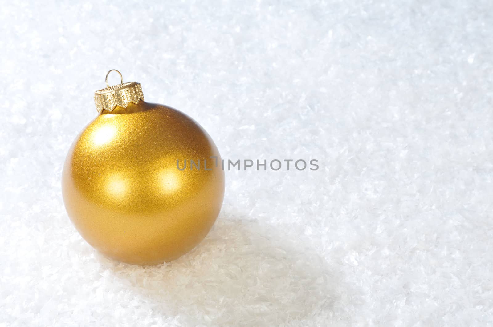 Gold christmas ball on white snow