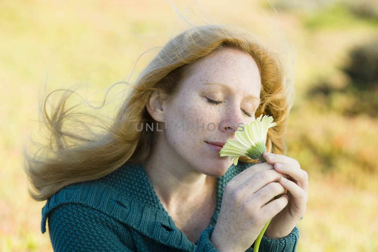 Portrait of a Pretty Redhead Woman Smelling a Flower
