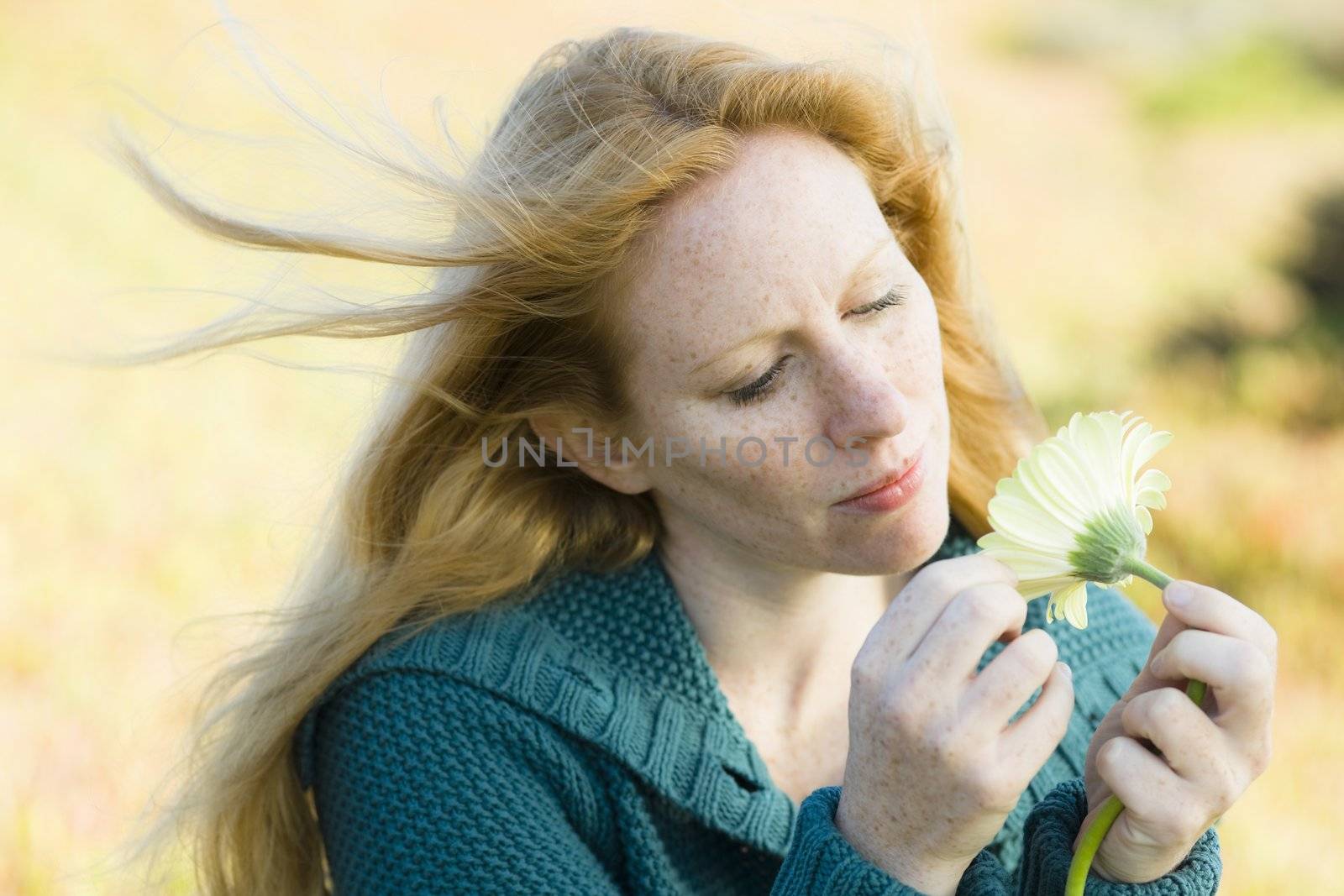 Portrait of a Pretty Redhead Woman Looking at a Flower