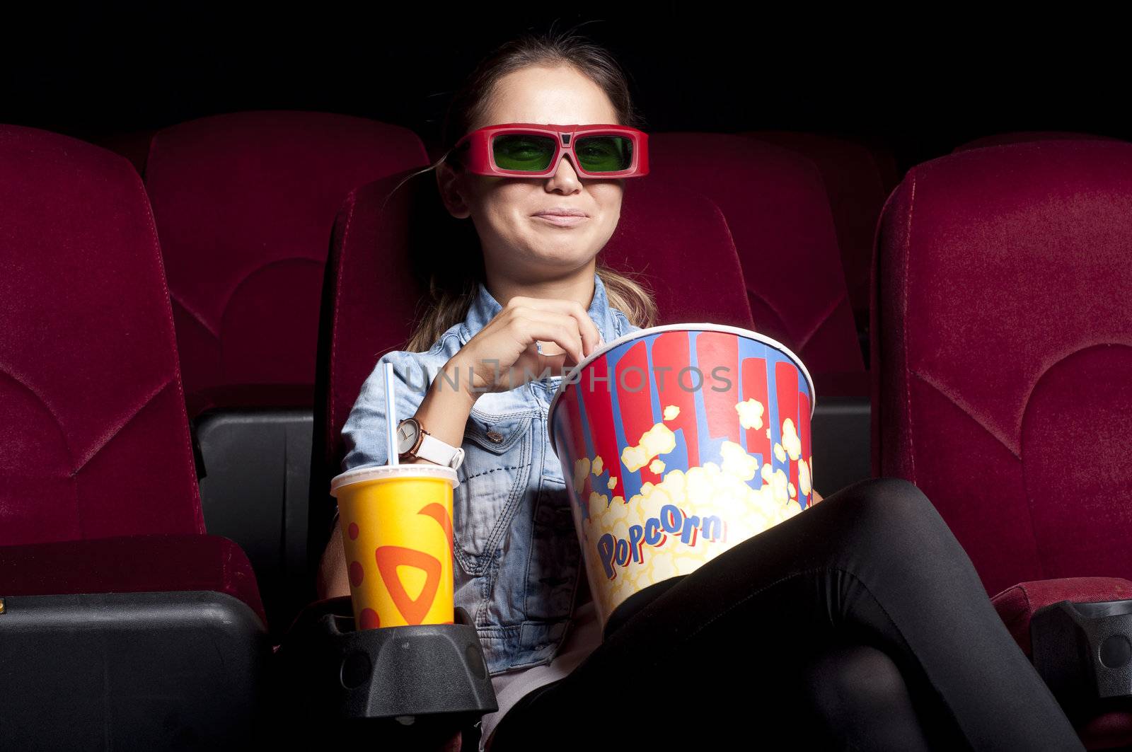 young woman sitting alone in the cinema and watching a movie