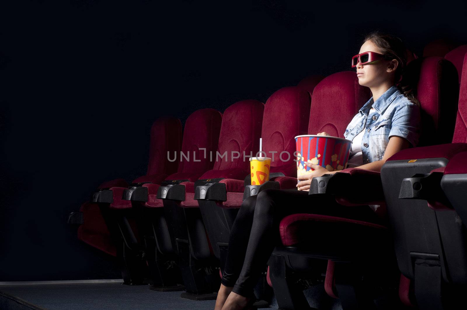 young woman sitting alone in the cinema and watching a movie