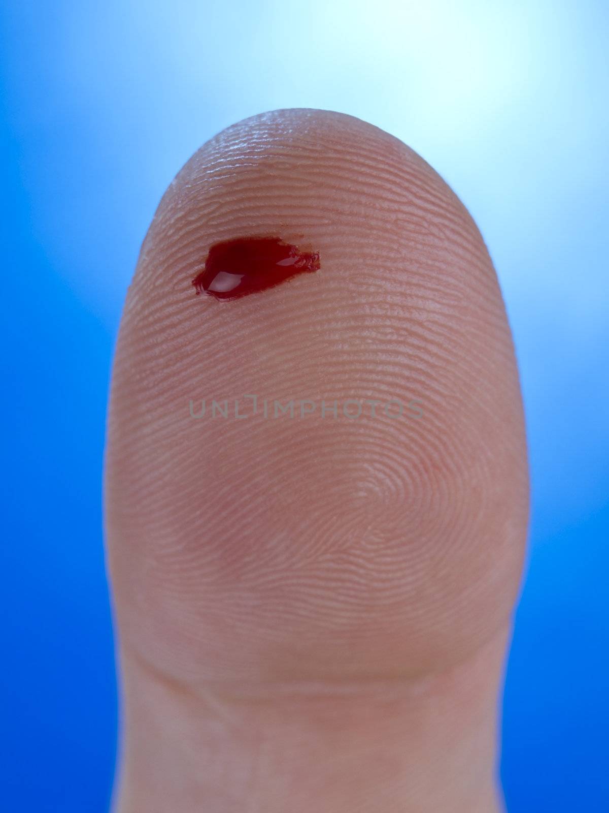 Macro view of a drop of real blood on a human thumb.