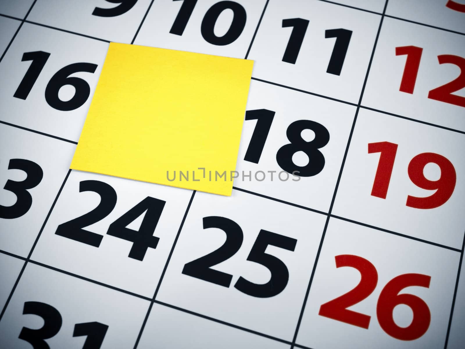 Close up of a blank sticky note on a calendar.