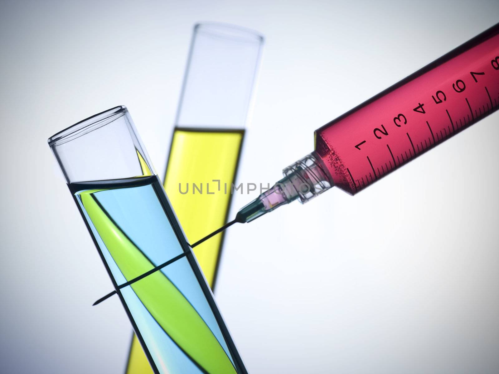 A syringe and two test tubes filled with color liquids.