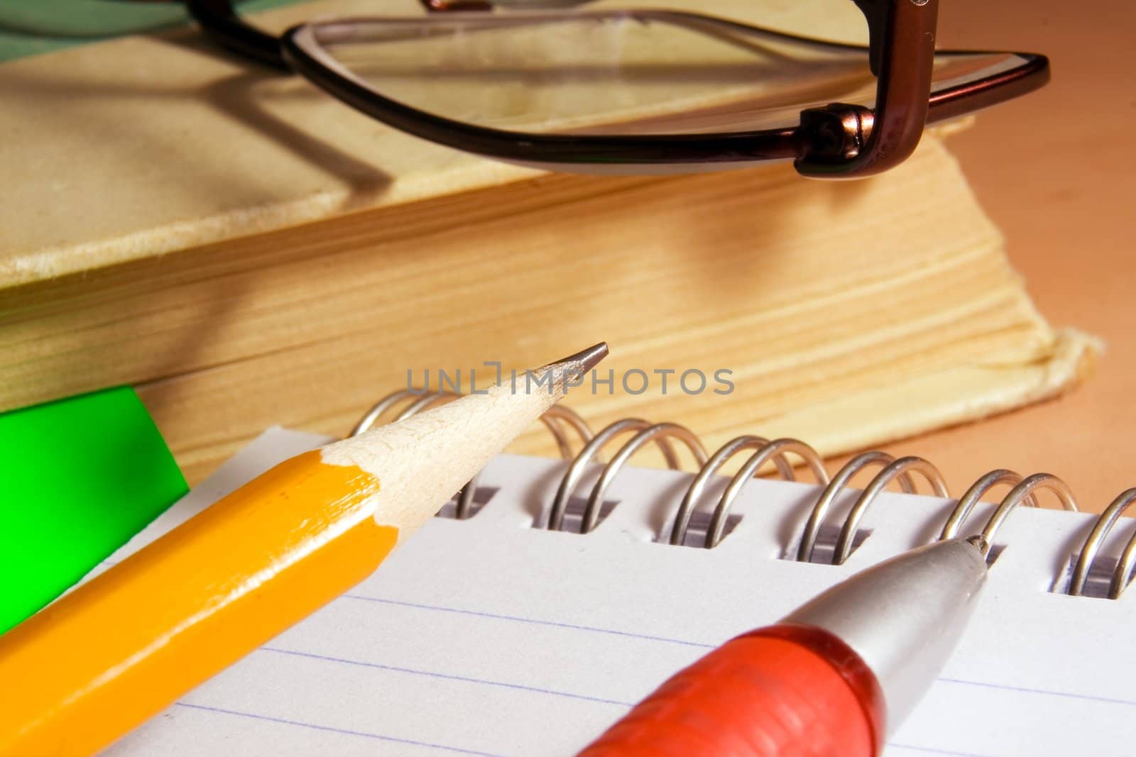 Notebook for notes, the book, the handle, a pencil, glasses on a desktop