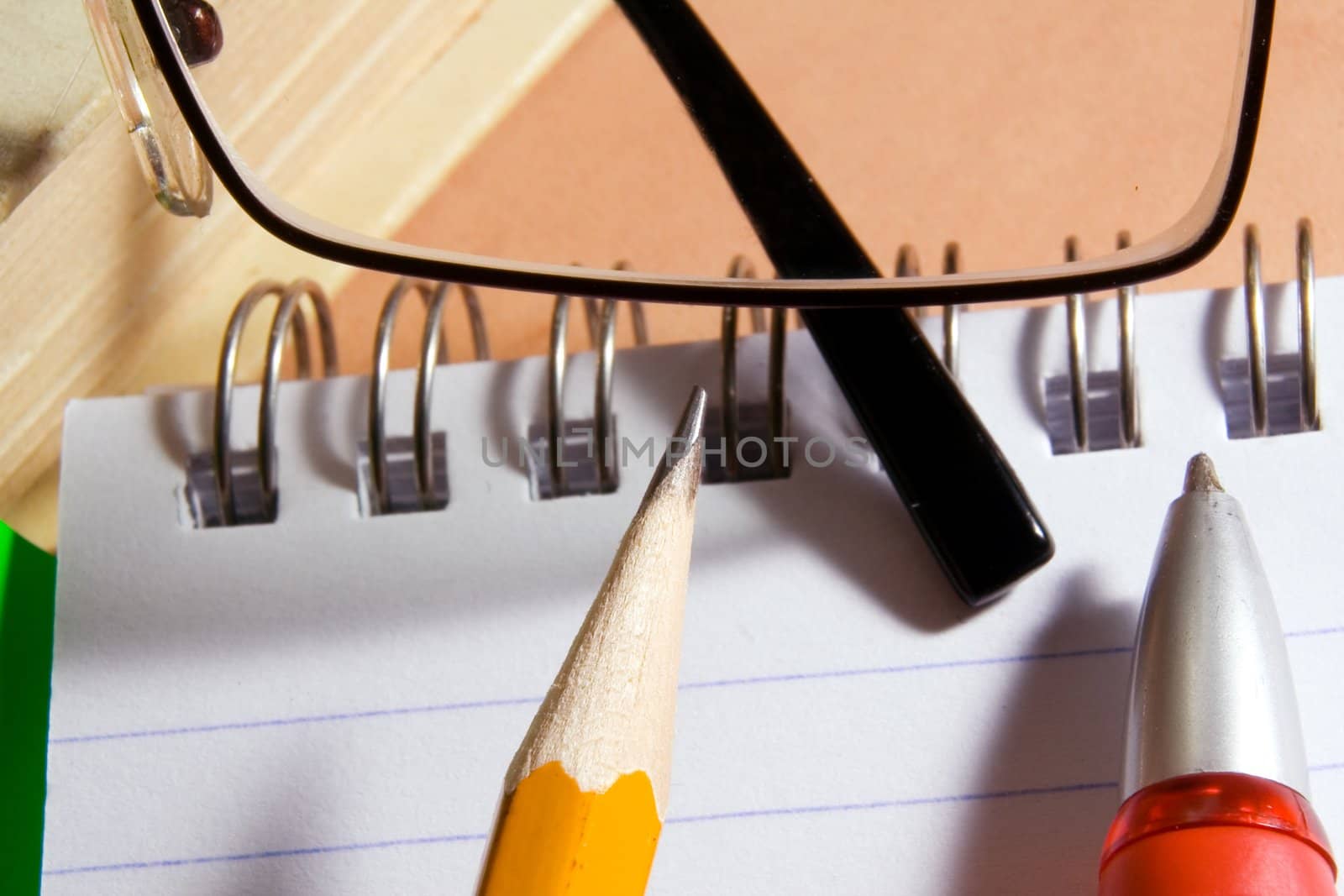 Notebook for notes, the book, the pen, a pencil, glasses on a desktop