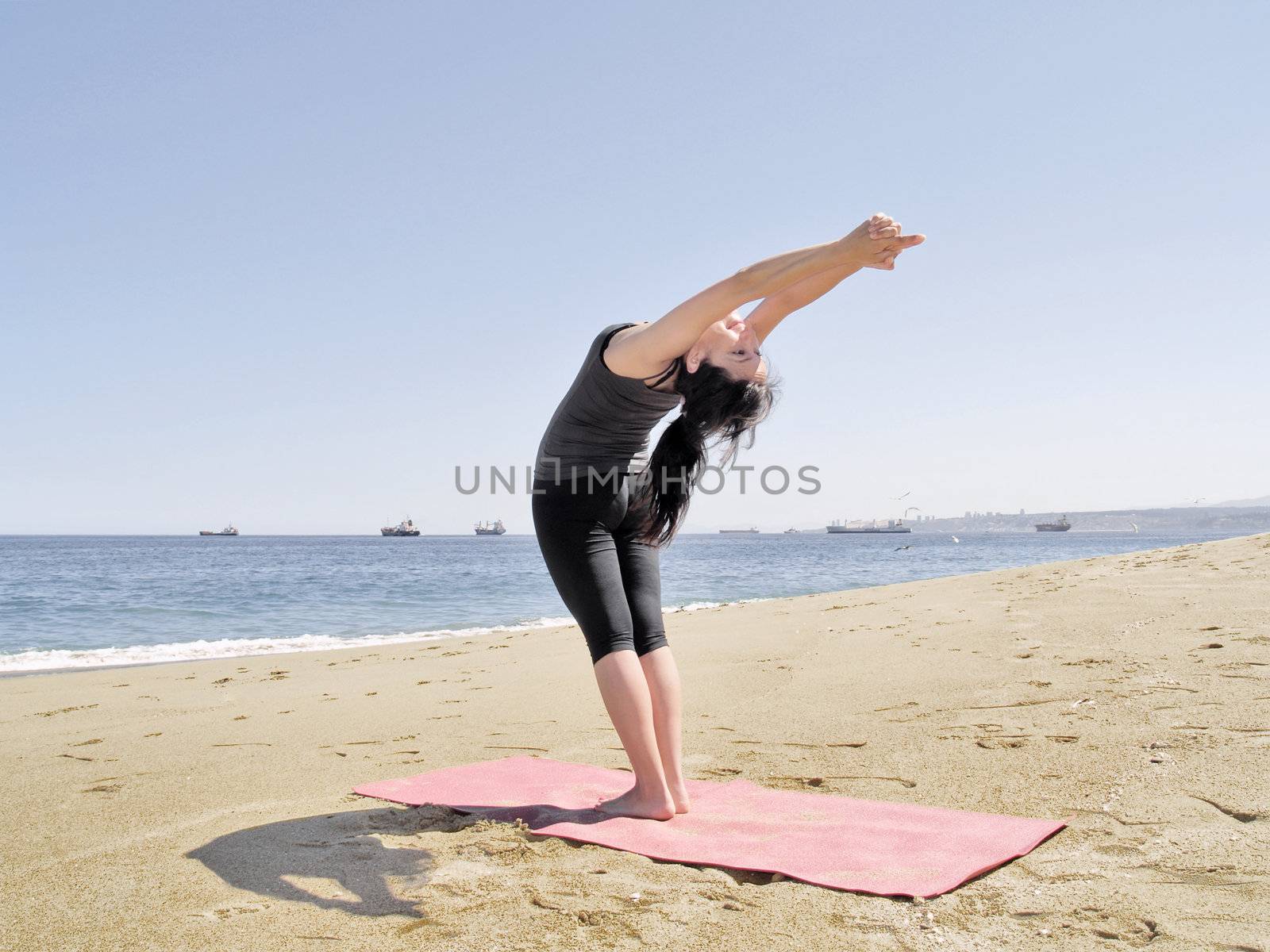 Yoga teacher practising at the beach pose arda chandrasana