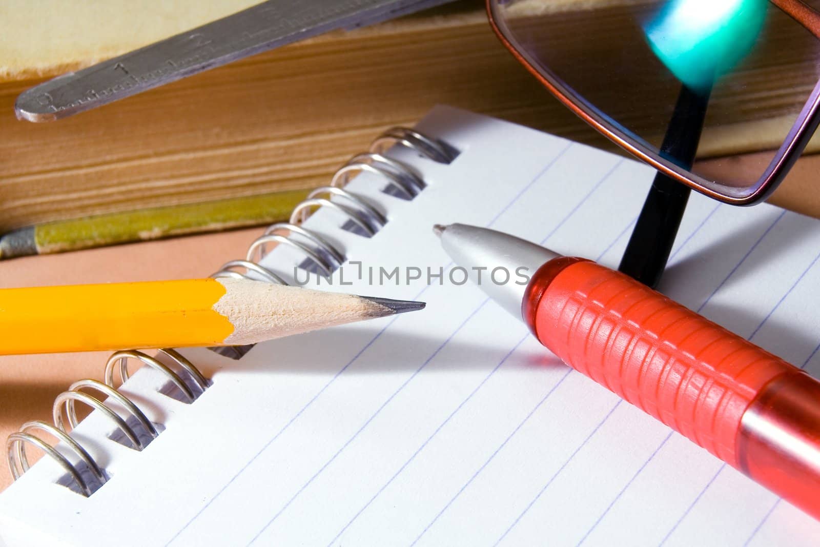 Notebook for notes, the book, the pen, a pencil, glasses on a desktop