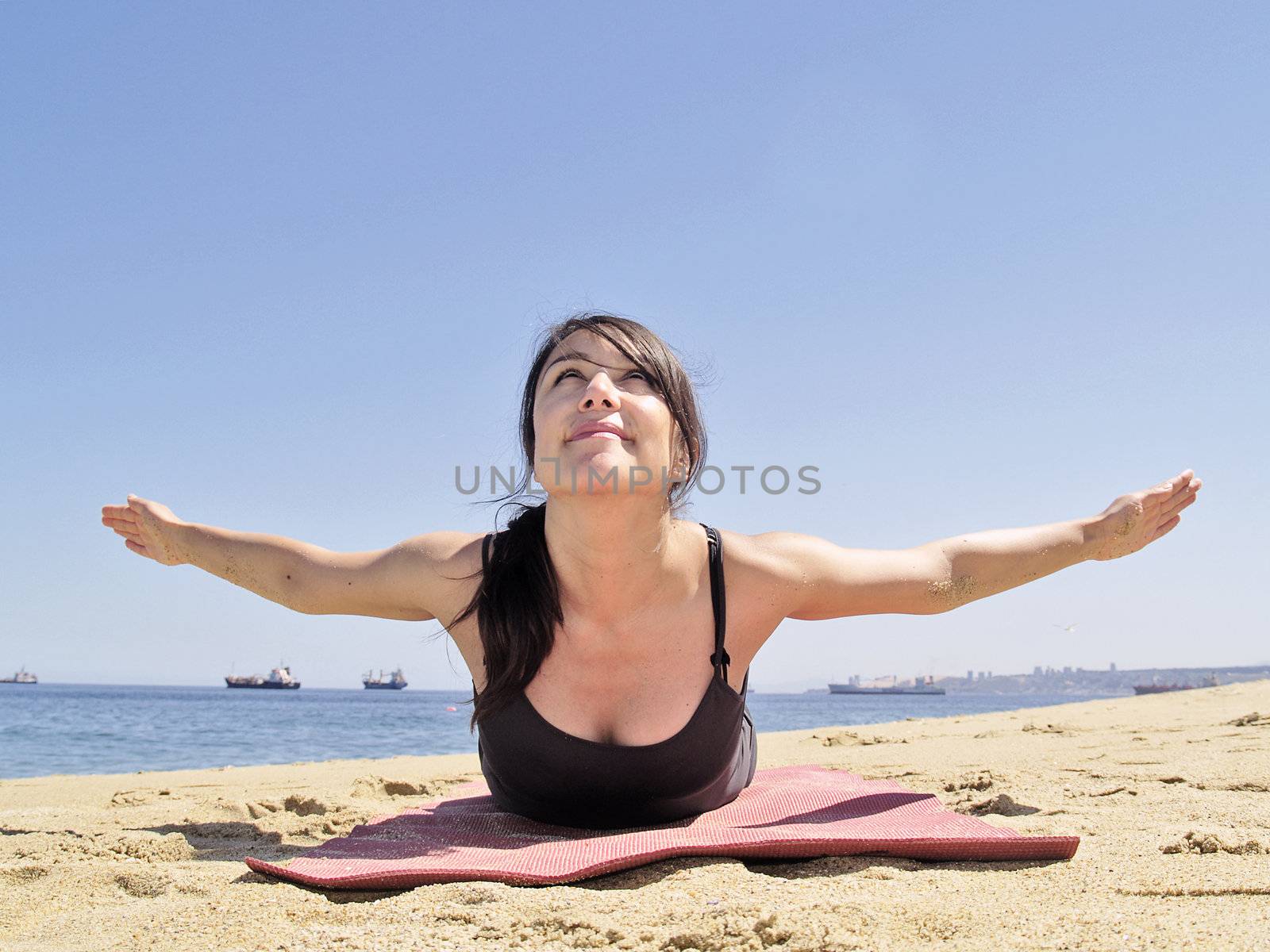 Yoga teacher practising at the beach pose paorna salabhasana
