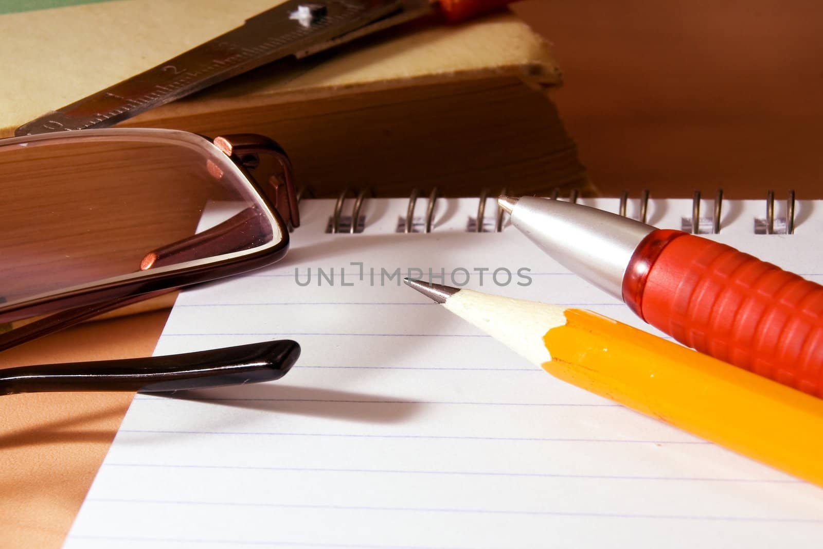 Notebook for notes, the book, the pen, a pencil, glasses on a desktop