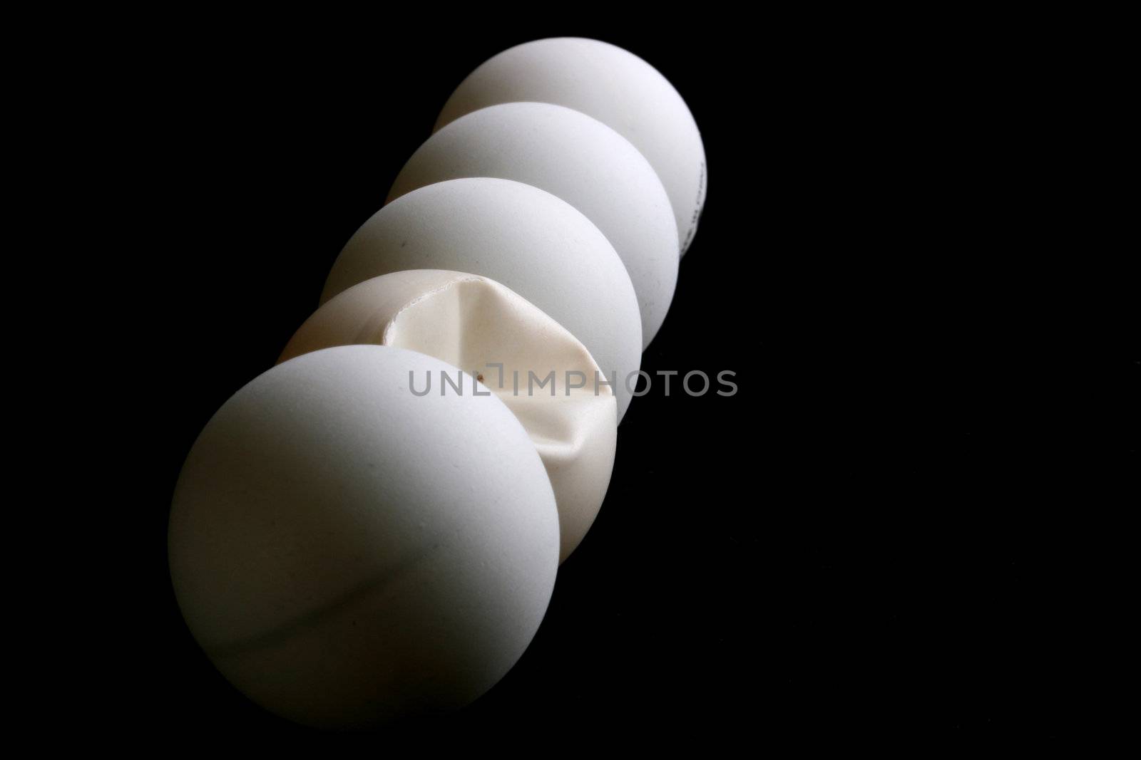 Five balls for game in table tennis on a black background. One ball is rumpled in game.