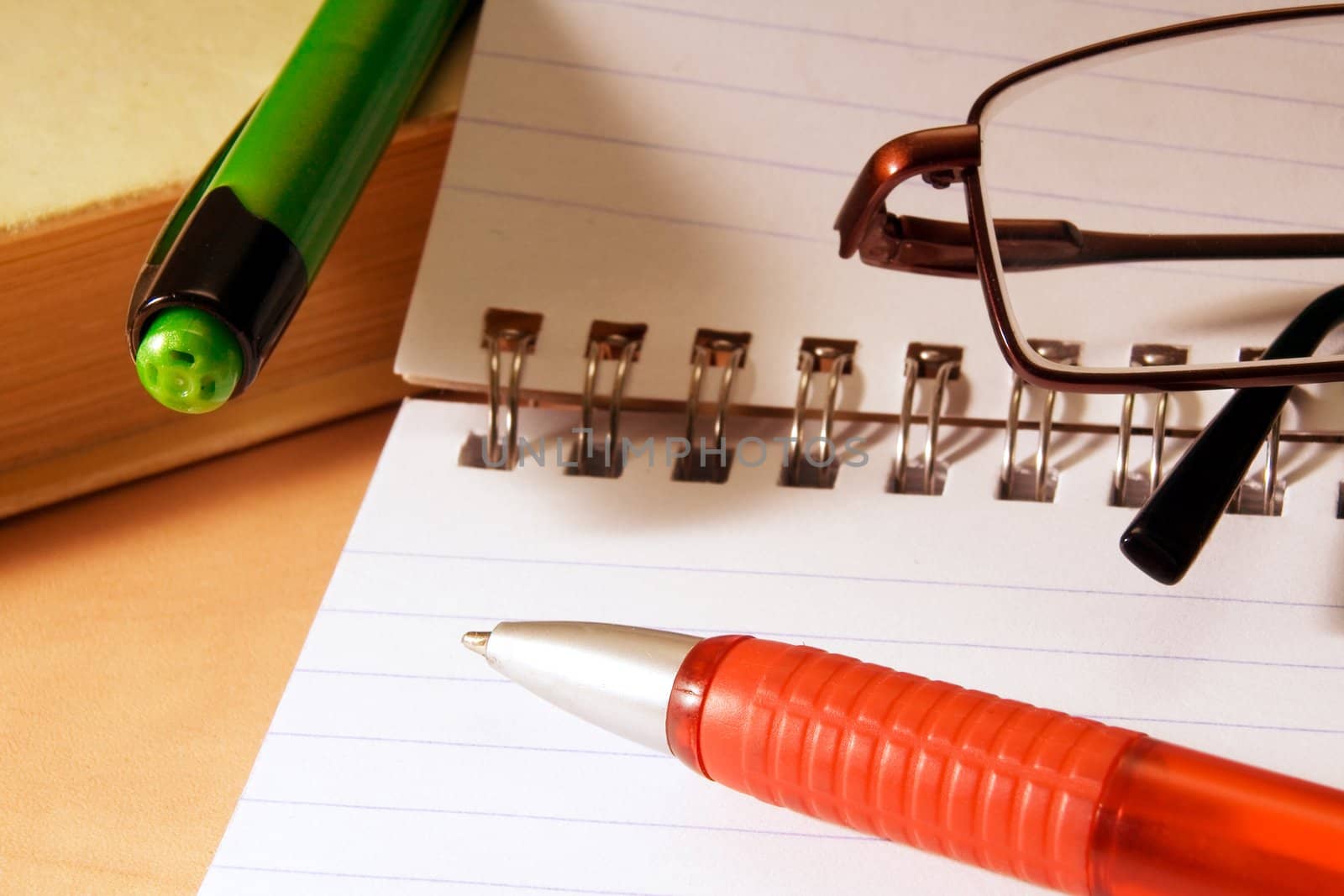 Notebook for notes, the book, the pen,  glasses on a desktop