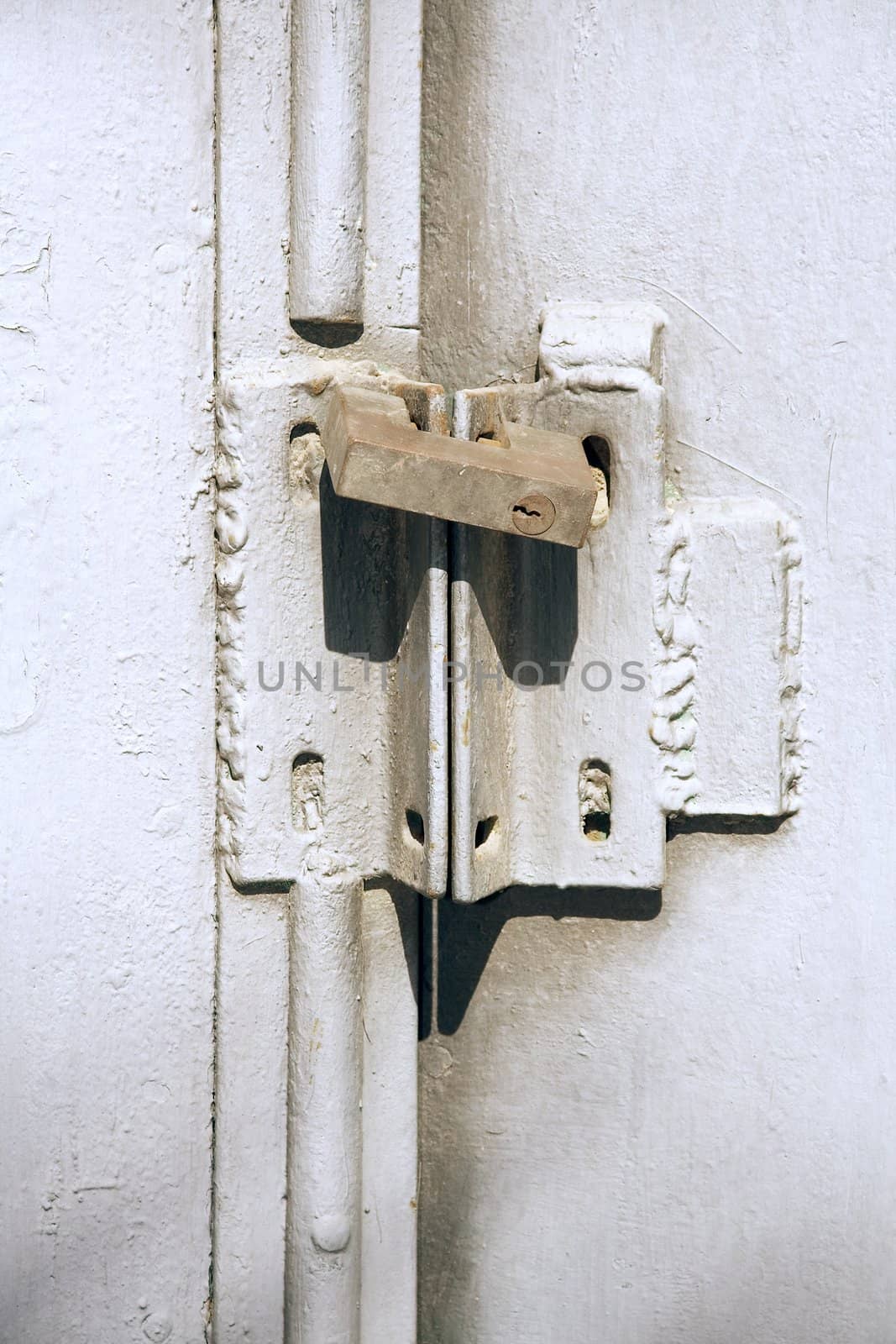 Old iron door painted in grey colour closed on the padlock