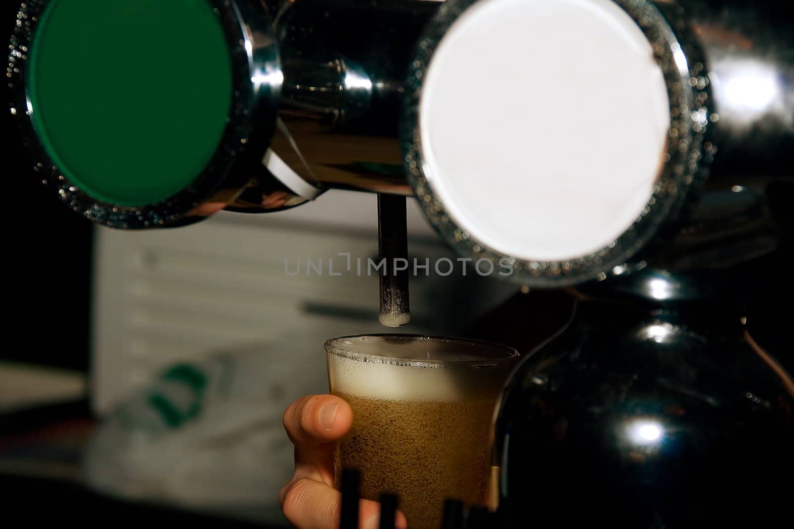 Hands of the bartender pouring beer from cranes in  mugs