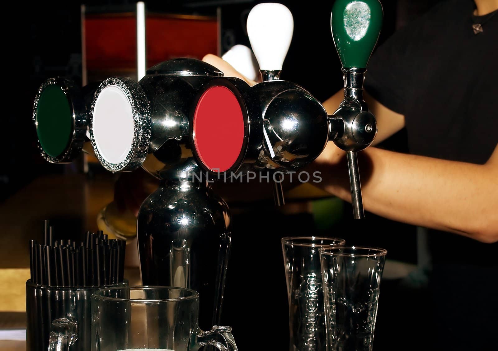 Hands of the bartender pouring beer from cranes in  mugs