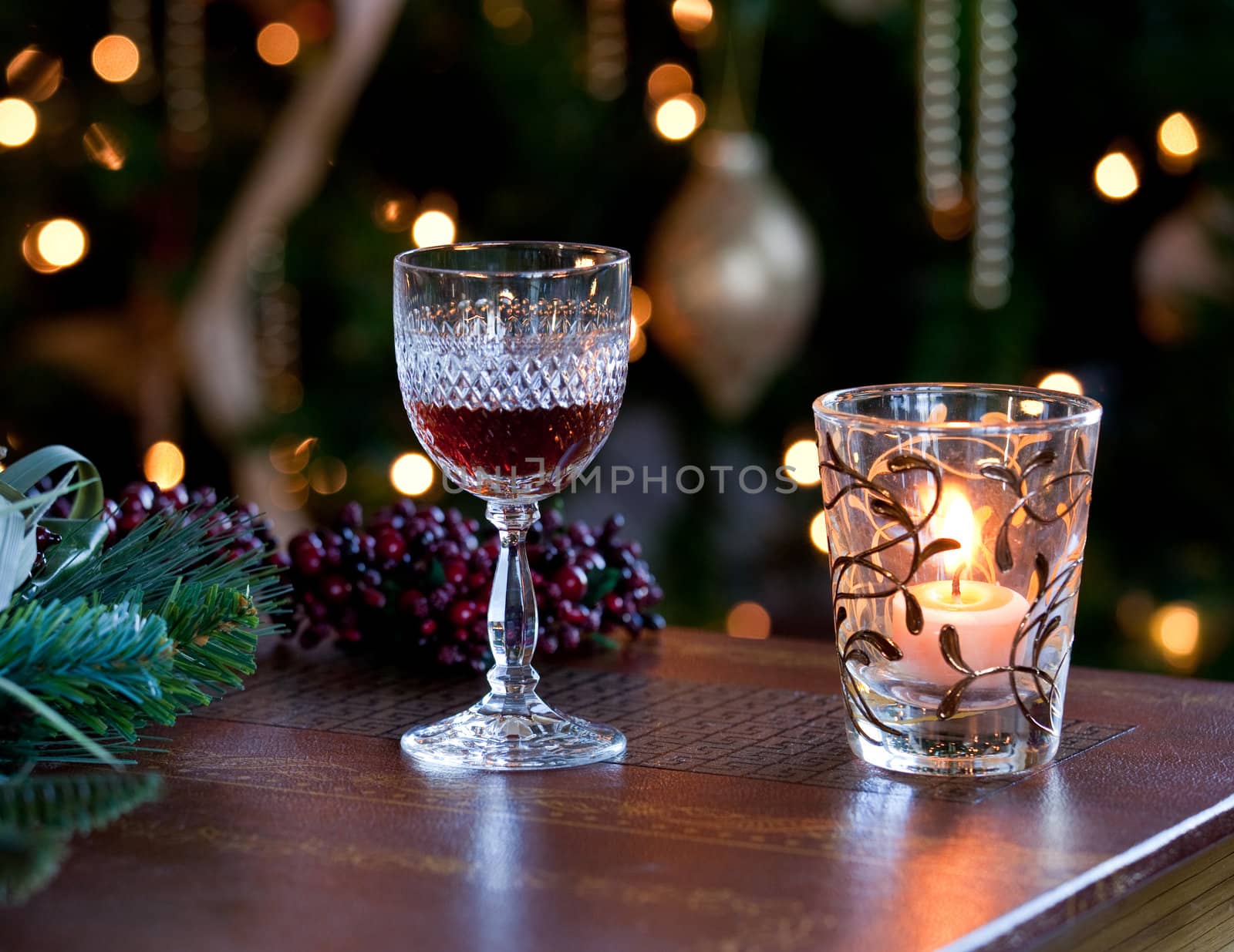 Cut glass sherry or port in front of xmas tree with cranberries and lit by candle