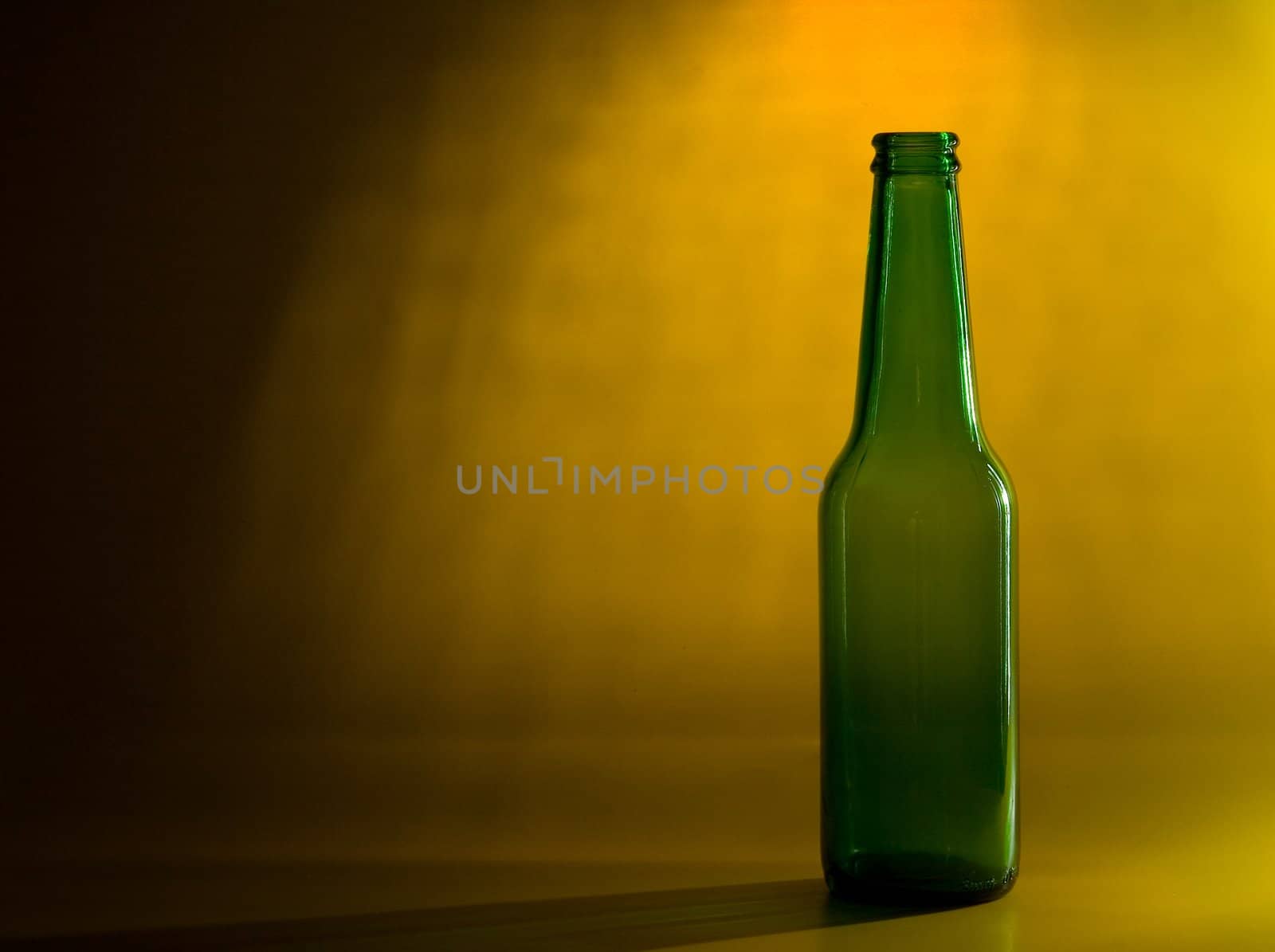 Green empty transparent glass bottle on color background