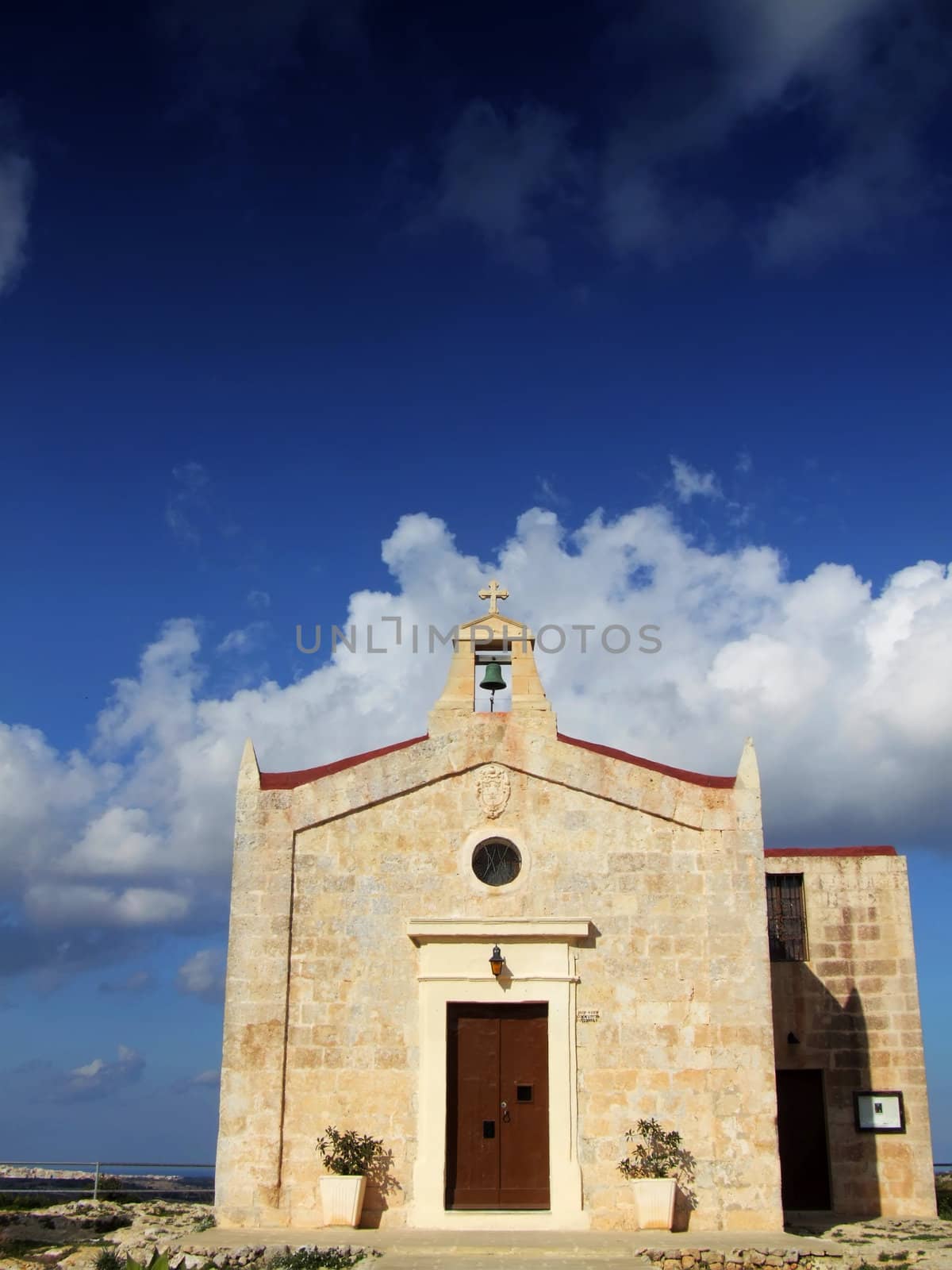 A medieval little chapel against blue sky and clouds