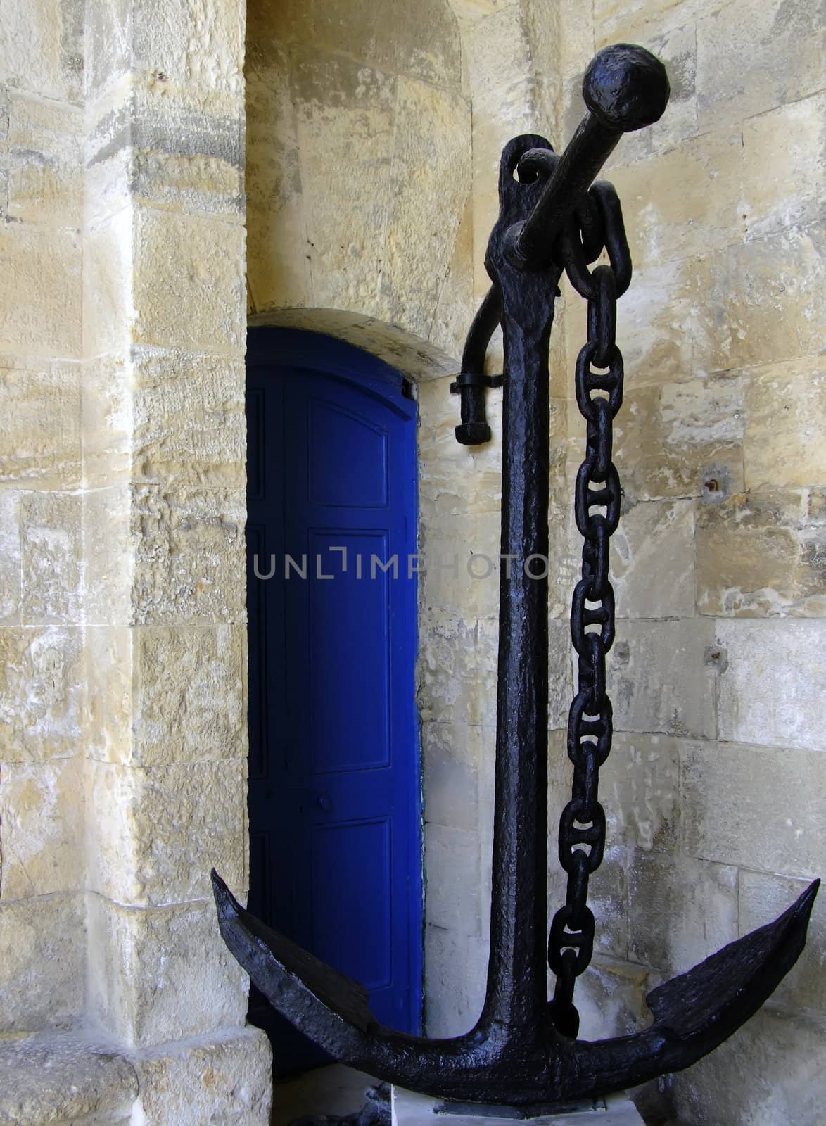 Old medieval anchor lying propped against limestone wall in Malta