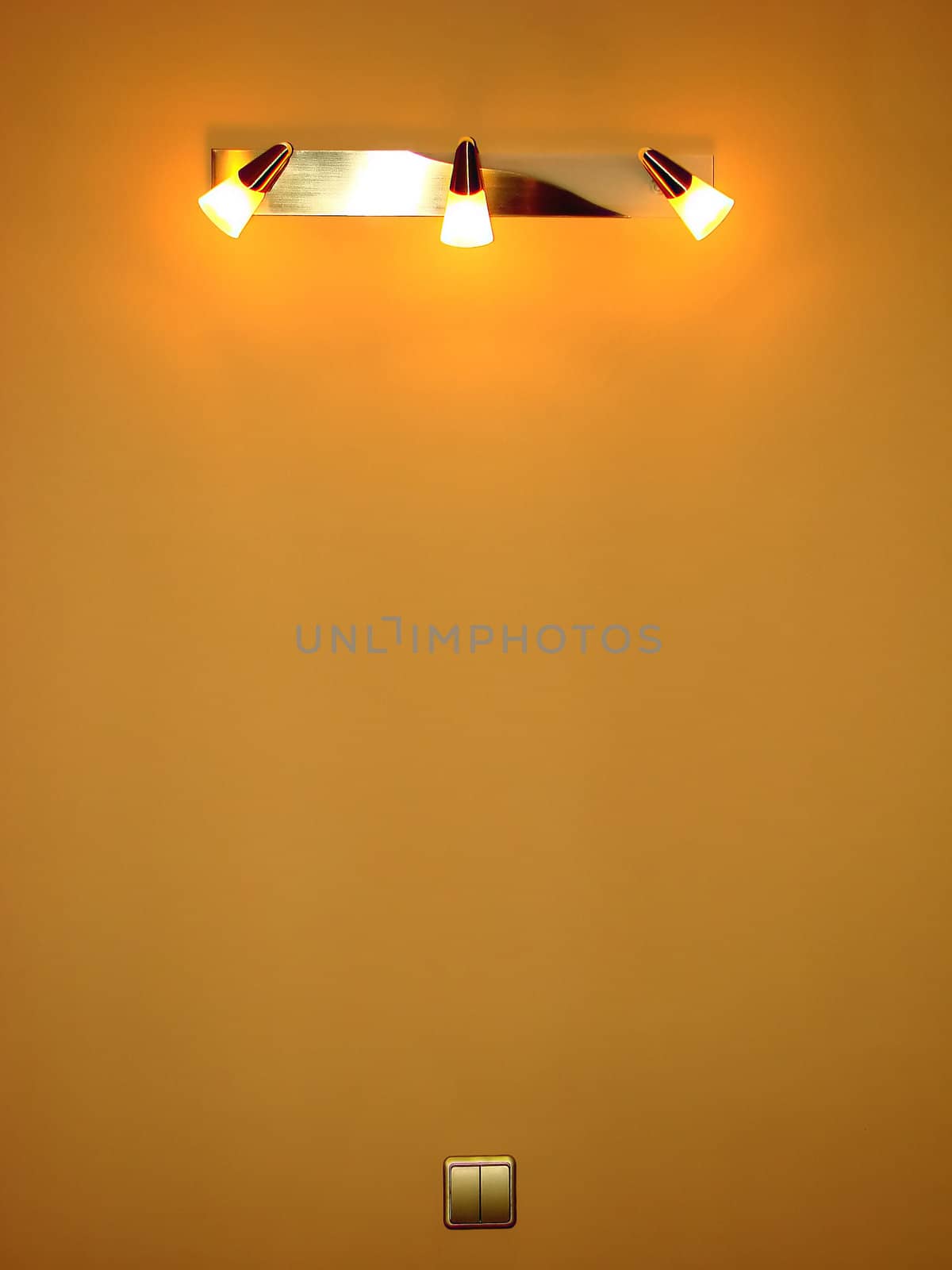 Switched on on a wall of a sconce consisting of three fixtures in a room after repair