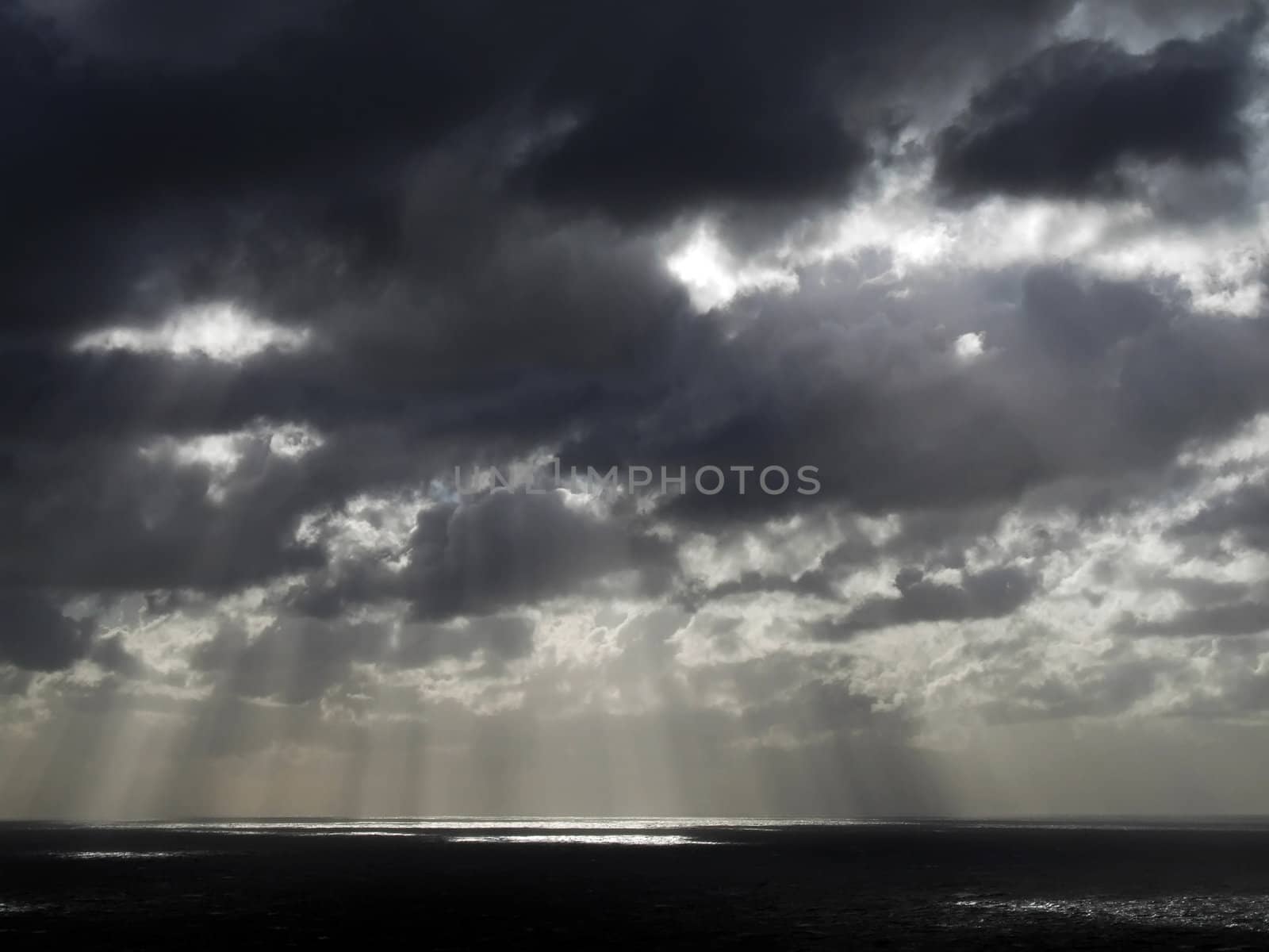 Clouds looming over the horizon with rays seeping through cast