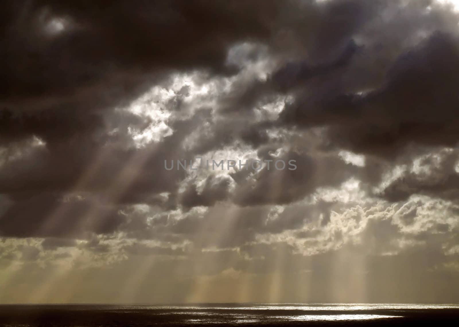 Clouds looming over the horizon with rays seeping through cast