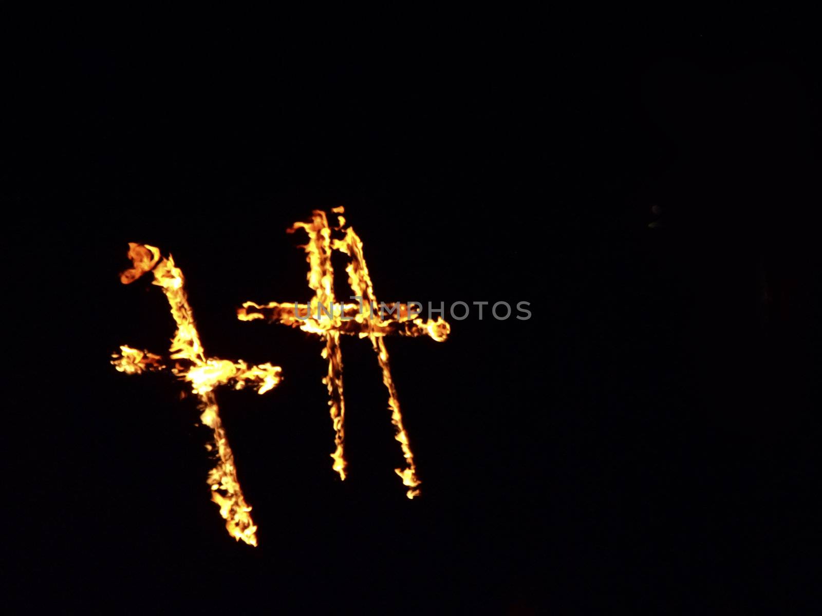 Burning crosses being used as part of ritual, on black background