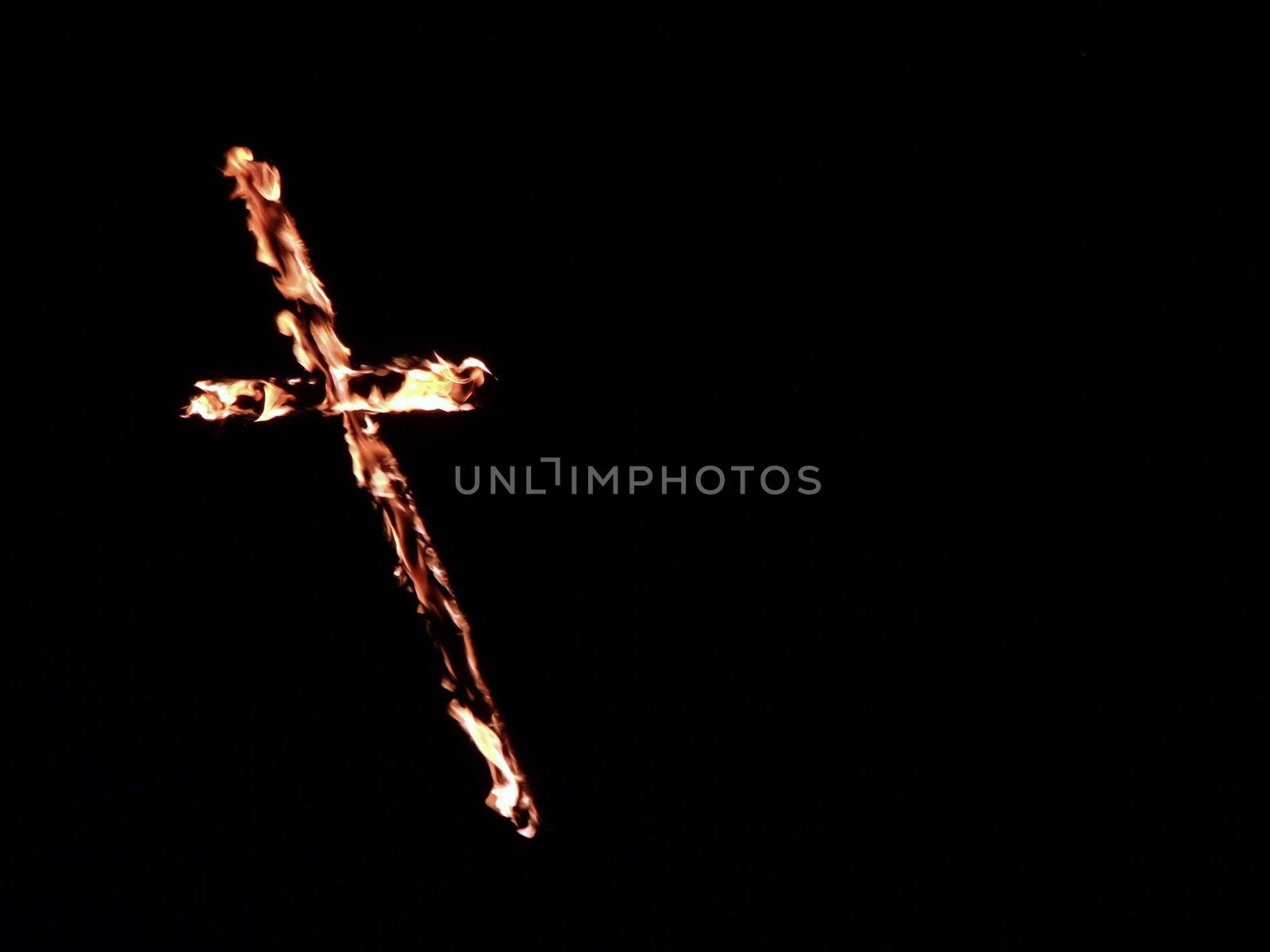 Burning crosses being used as part of ritual, on black background