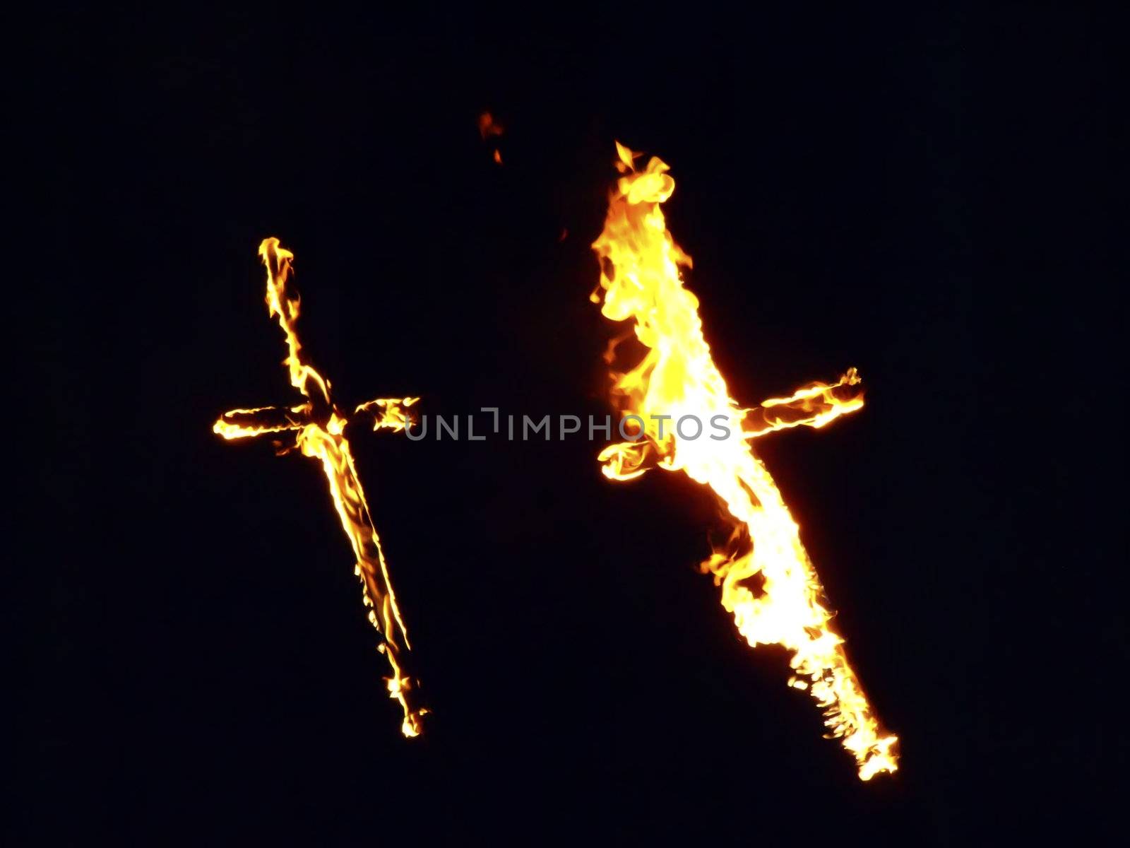 Burning crosses being used as part of ritual, on black background