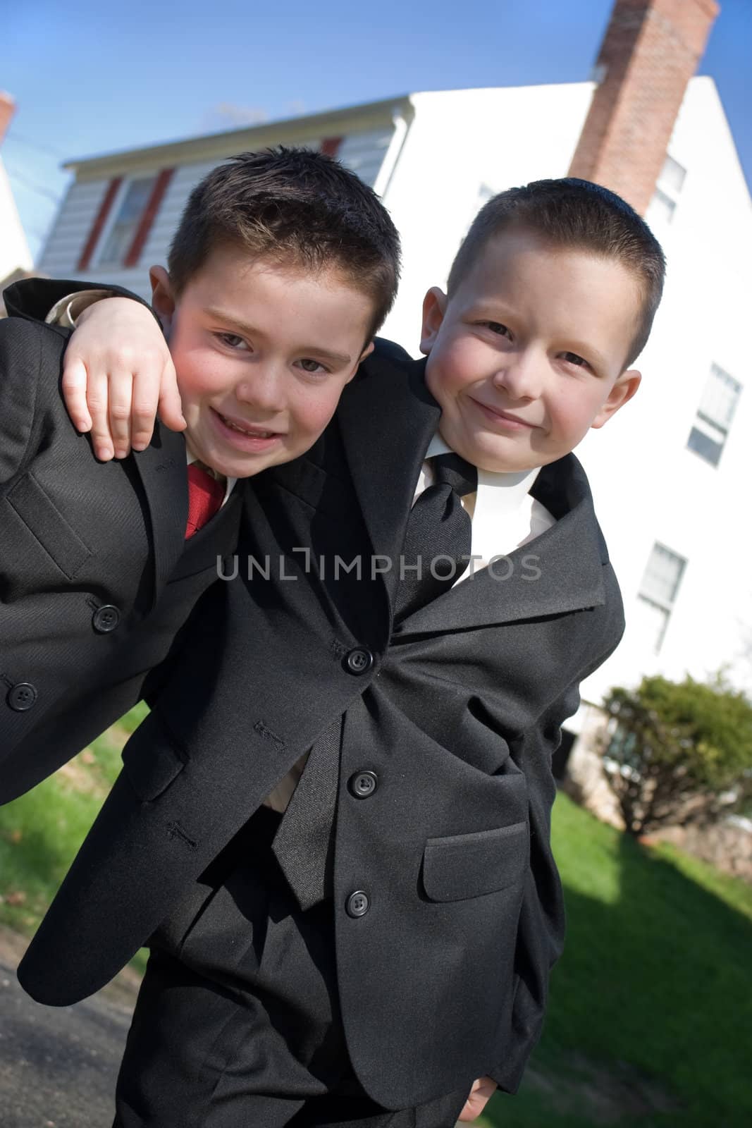 Two happy young boys dressed in suits with smiles on their faces.