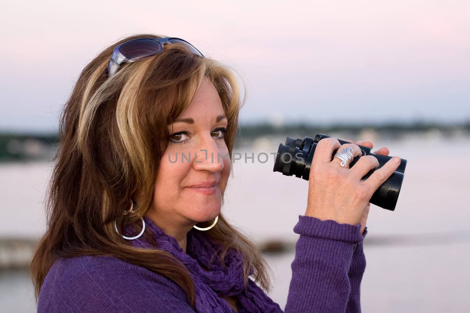 A woman looking with binoculars at the beach.