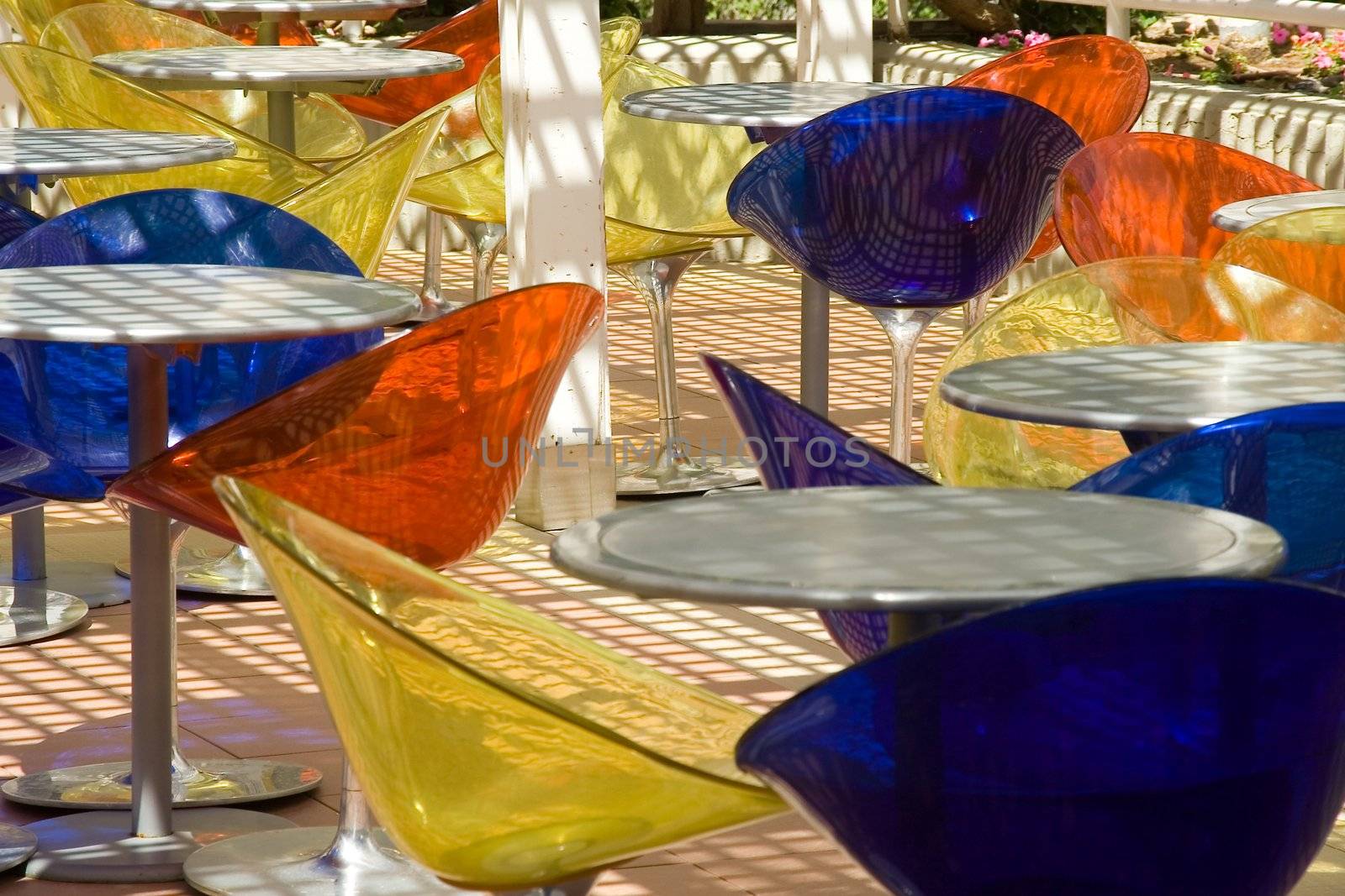 Summer cafe with round little tables and colour transparent plastic chairs