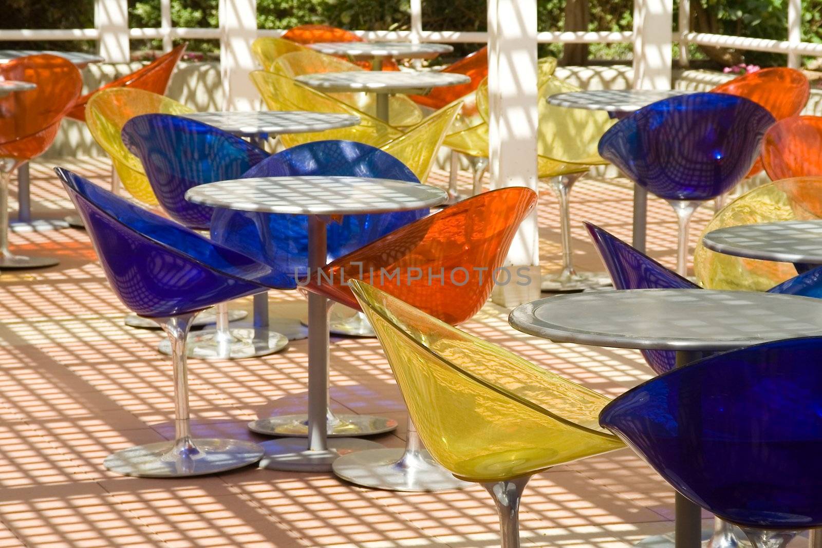 Summer cafe with round little tables and colour transparent plastic chairs