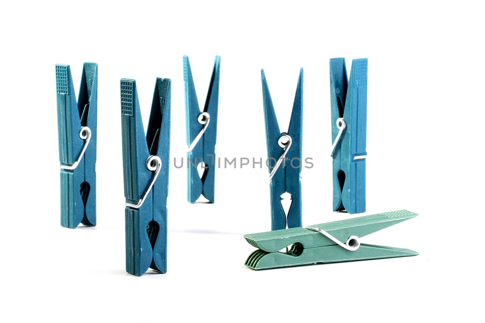 Dark blue plastic clothespins are placed on a table, the turquoise clothespin lies.