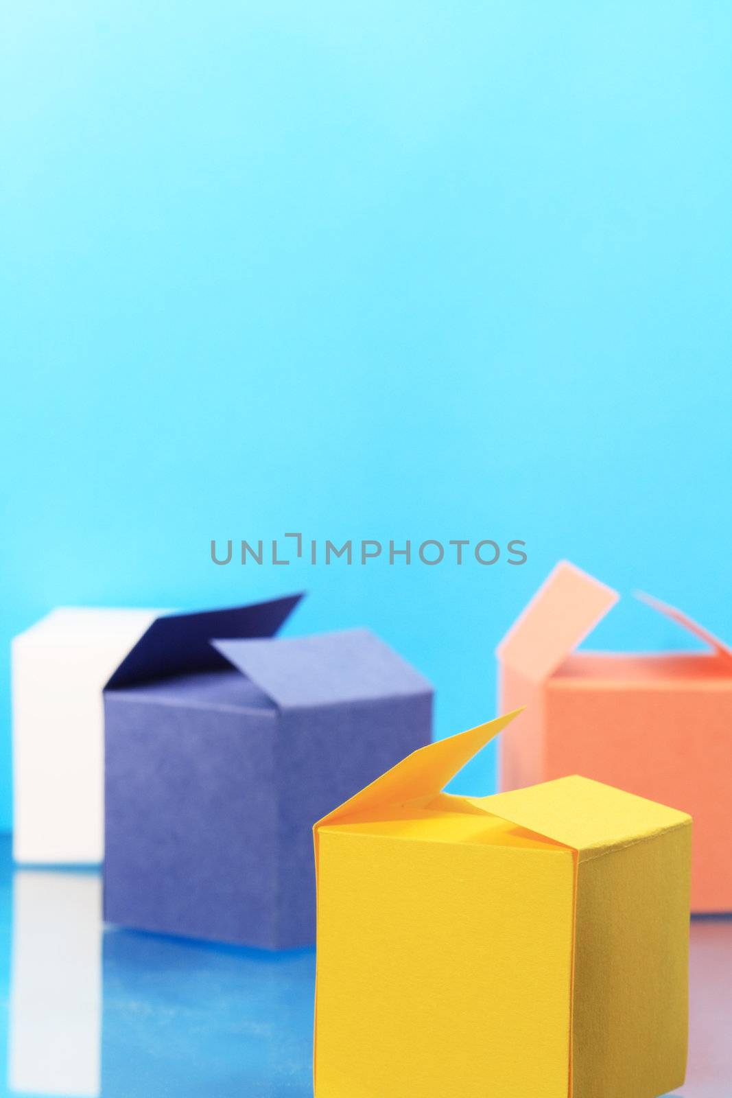 Four colored paper boxes on blue background with copy space