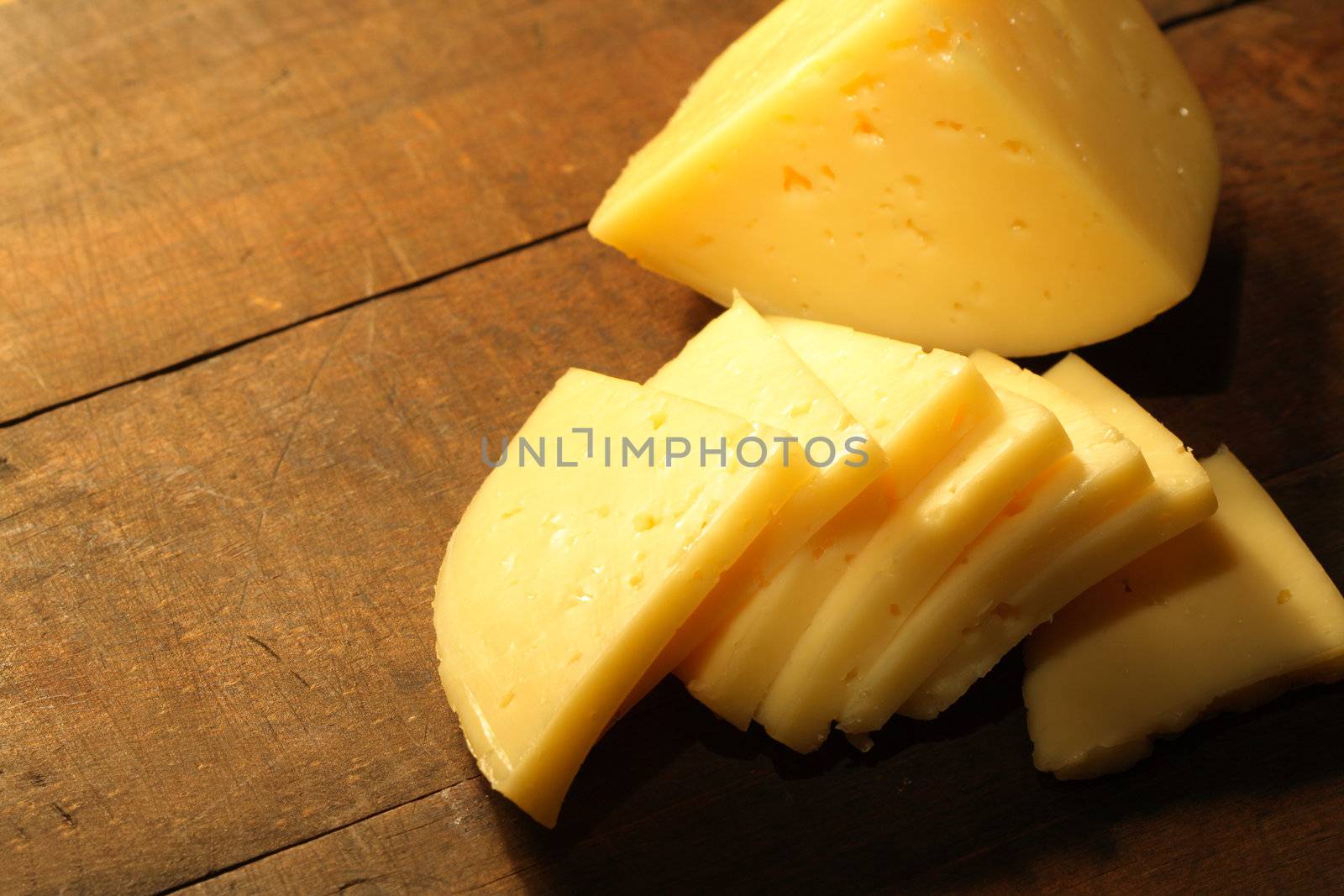 Closeup of sliced cheese lying on wooden table