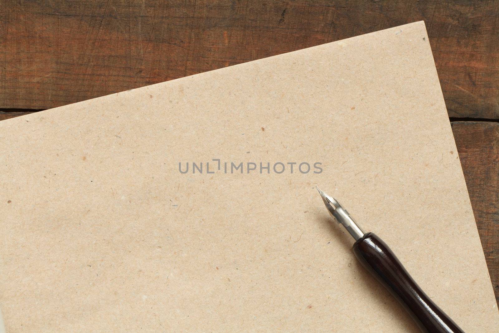 Sheet of rough paper and old fountain pen on wooden background