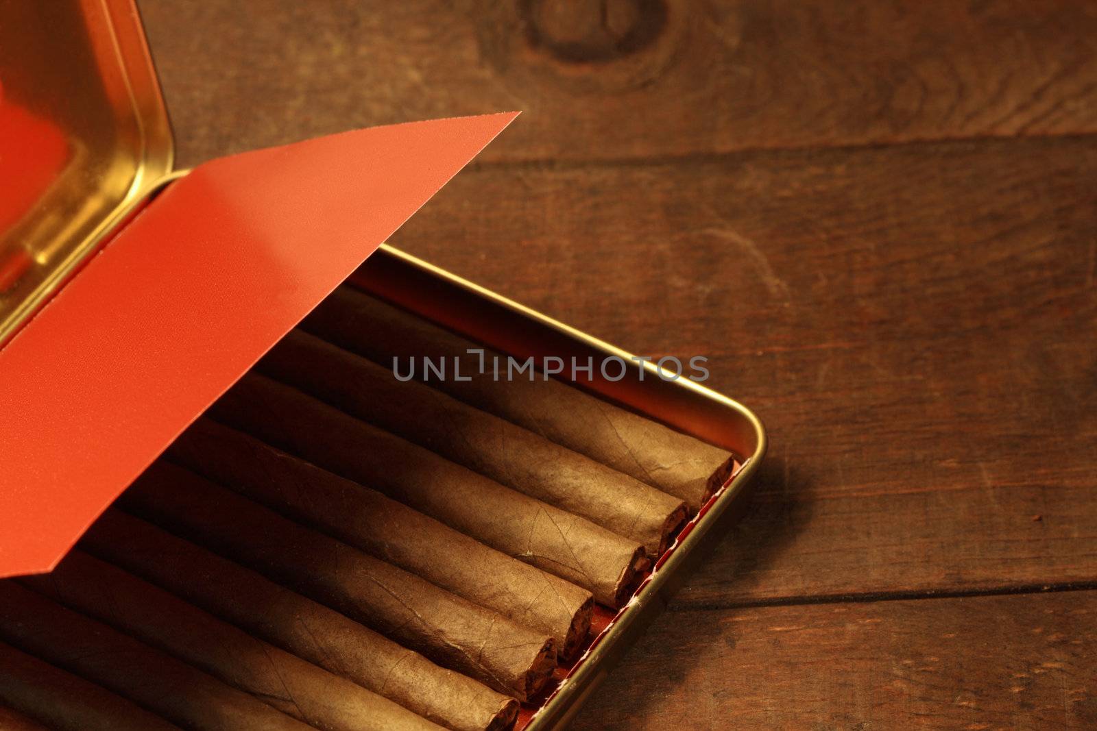 Open metal box of cigarillos isolated on wooden background