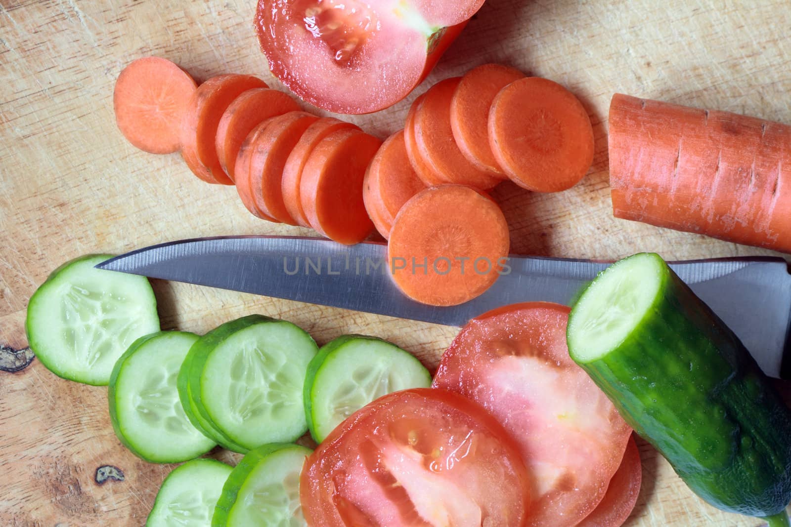 Closeup of various vegetables and kitchen knife on wooden background
