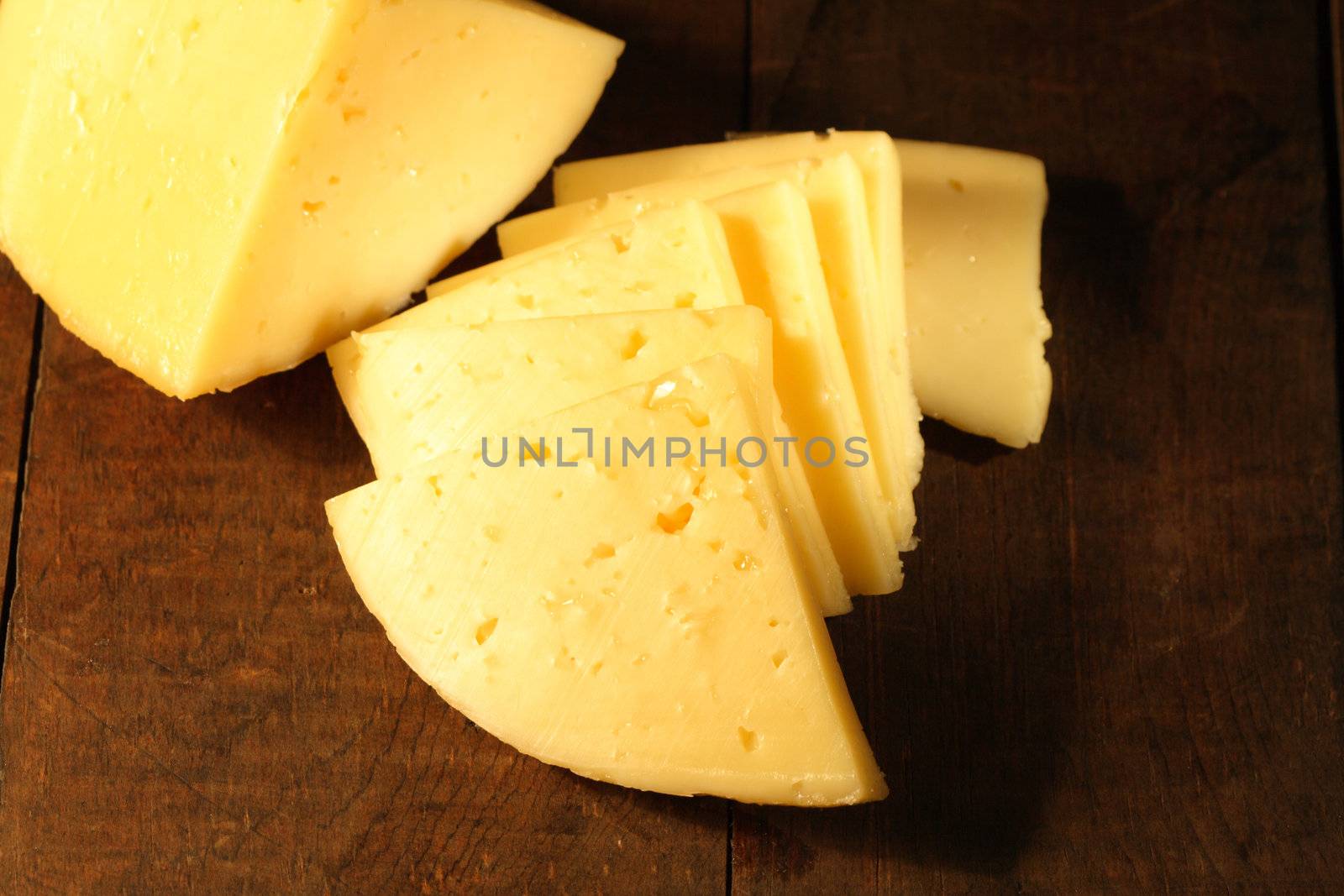 Closeup of sliced cheese lying on wooden table
