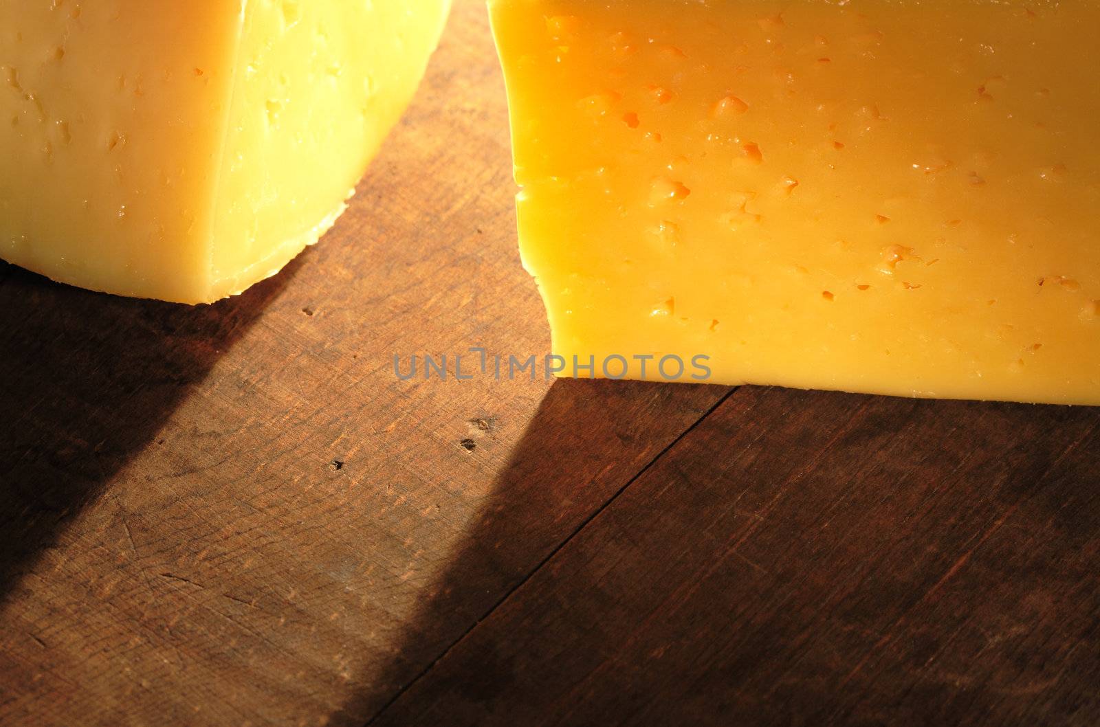 Closeup of two cheese pieces lying on wooden table