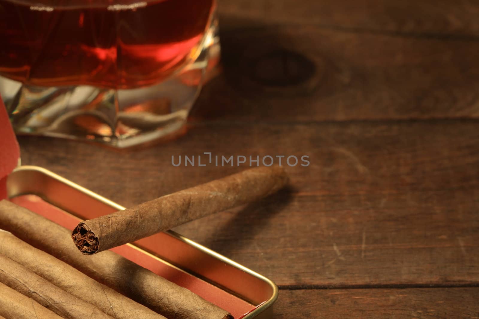 Metal box of cigars and glass of whiskey on wooden background
