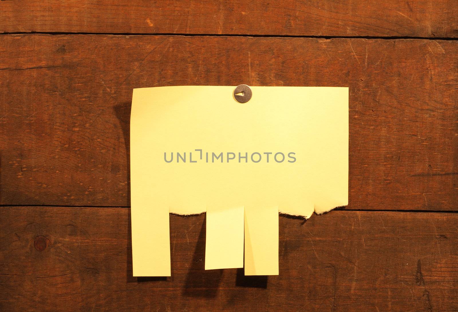 Yellow paper hanging on wooden background with thumbtacks